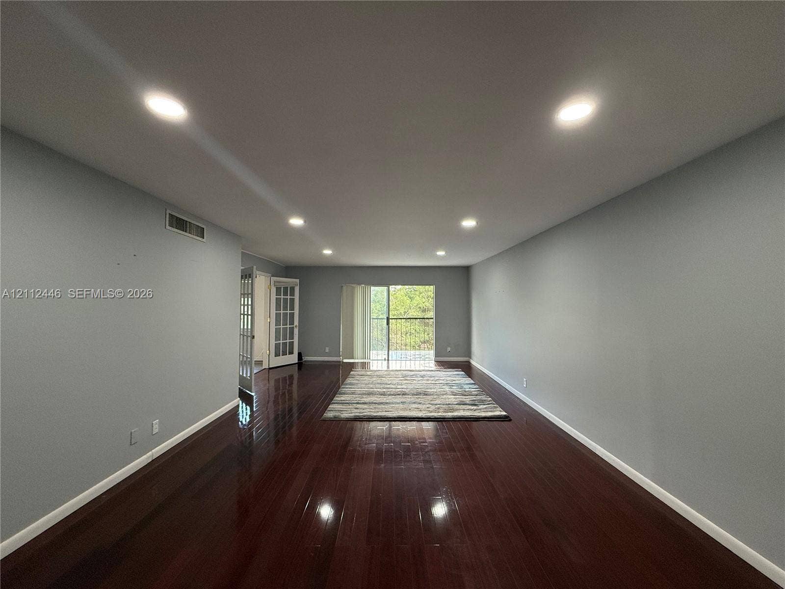 6100 S Falls Cir Drive, #411, Lauderhill, FL 33319 Interior room featuring dark wood-finish flooring, recessed lighting, and a glass-paneled sliding door opening to a balcony