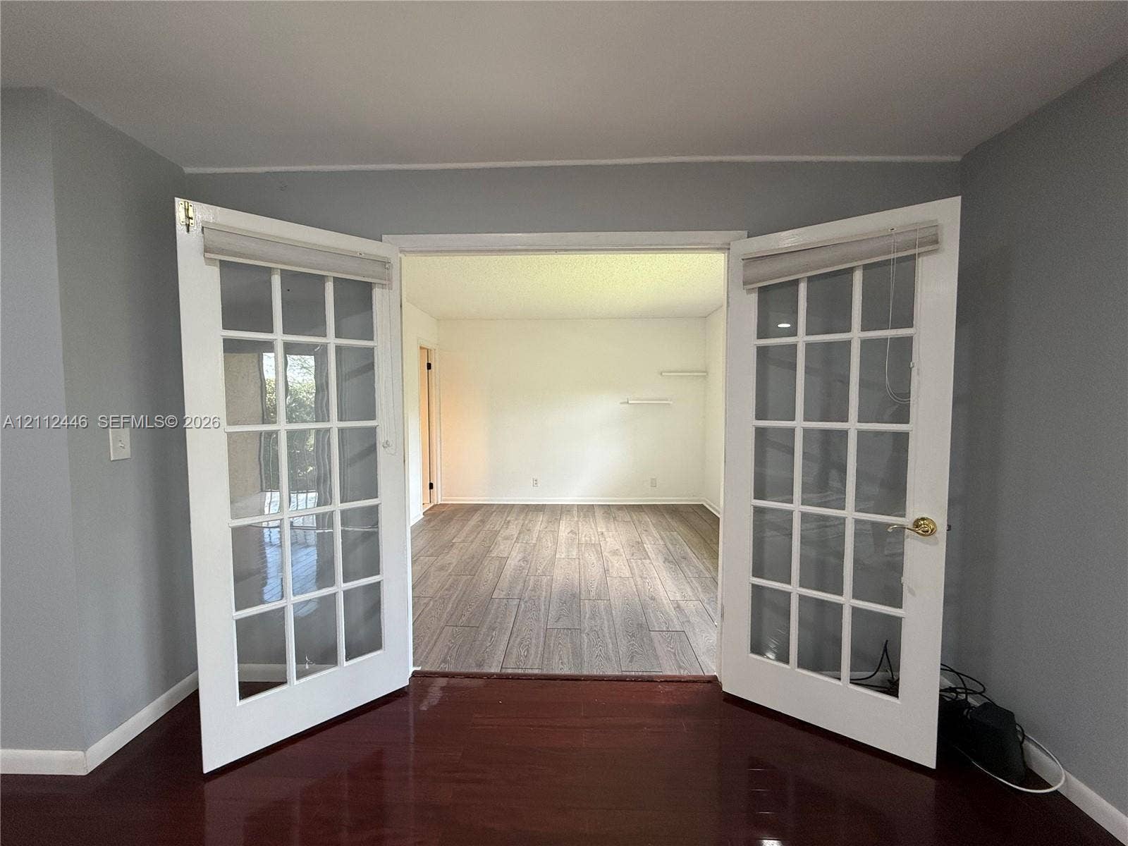 6100 S Falls Cir Drive, #411, Lauderhill, FL 33319 Double glass-paned doors featuring white frames, brass-finish hardware, and built-in blind fixtures, accented by wood-finish flooring
