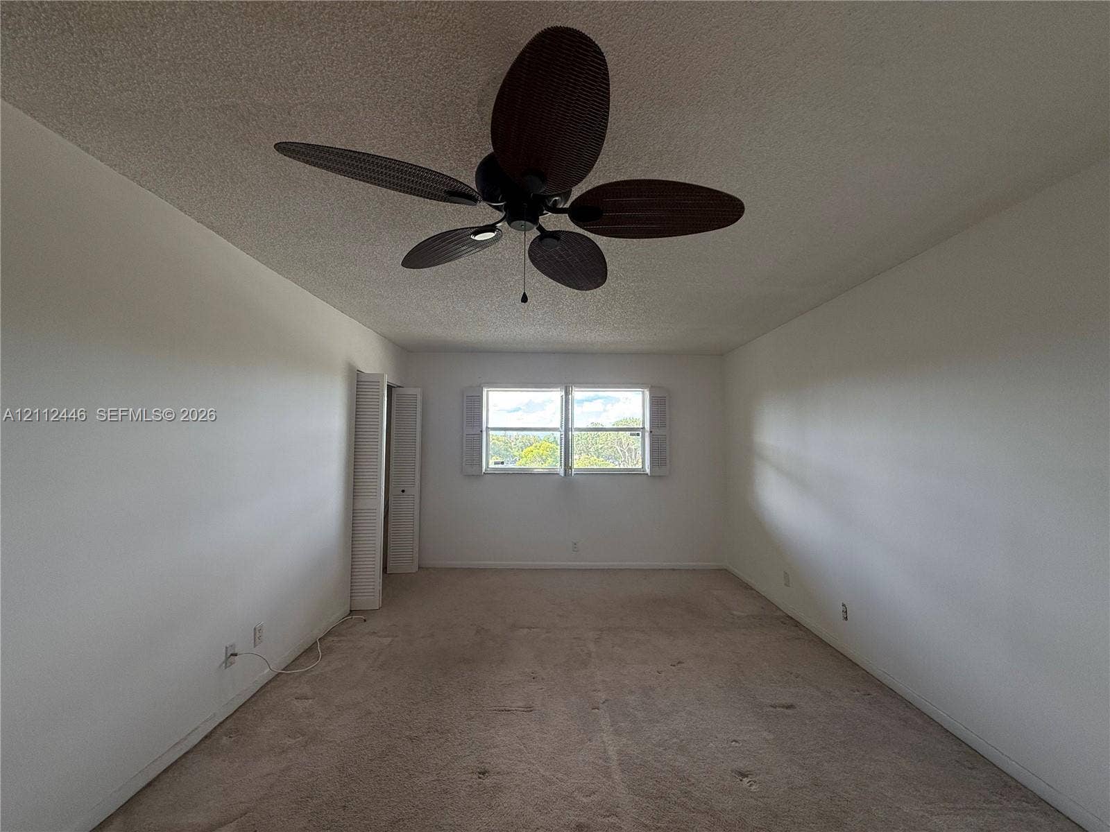 6100 S Falls Cir Drive, #411, Lauderhill, FL 33319 Room featuring a multi-blade ceiling fan, wall-to-wall carpeting, and double-hung windows with white shutters