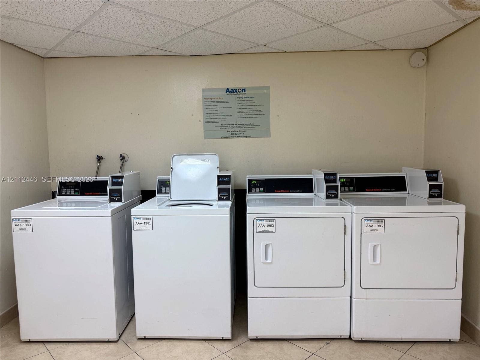6100 S Falls Cir Drive, #411, Lauderhill, FL 33319 Dedicated laundry area featuring multiple white top-load washers and front-load dryers with high-capacity controls and tile flooring