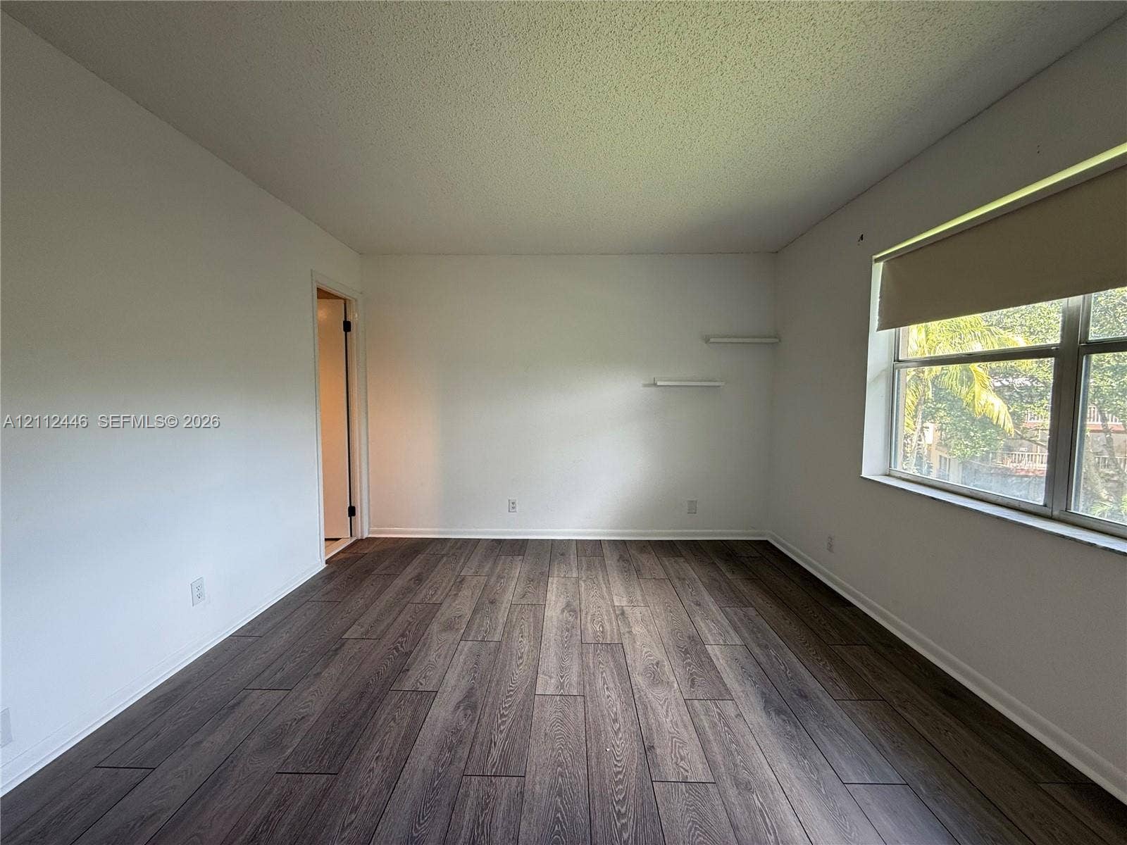 6100 S Falls Cir Drive, #411, Lauderhill, FL 33319 Room featuring wood-finish flooring, white walls, and built-in wall shelving