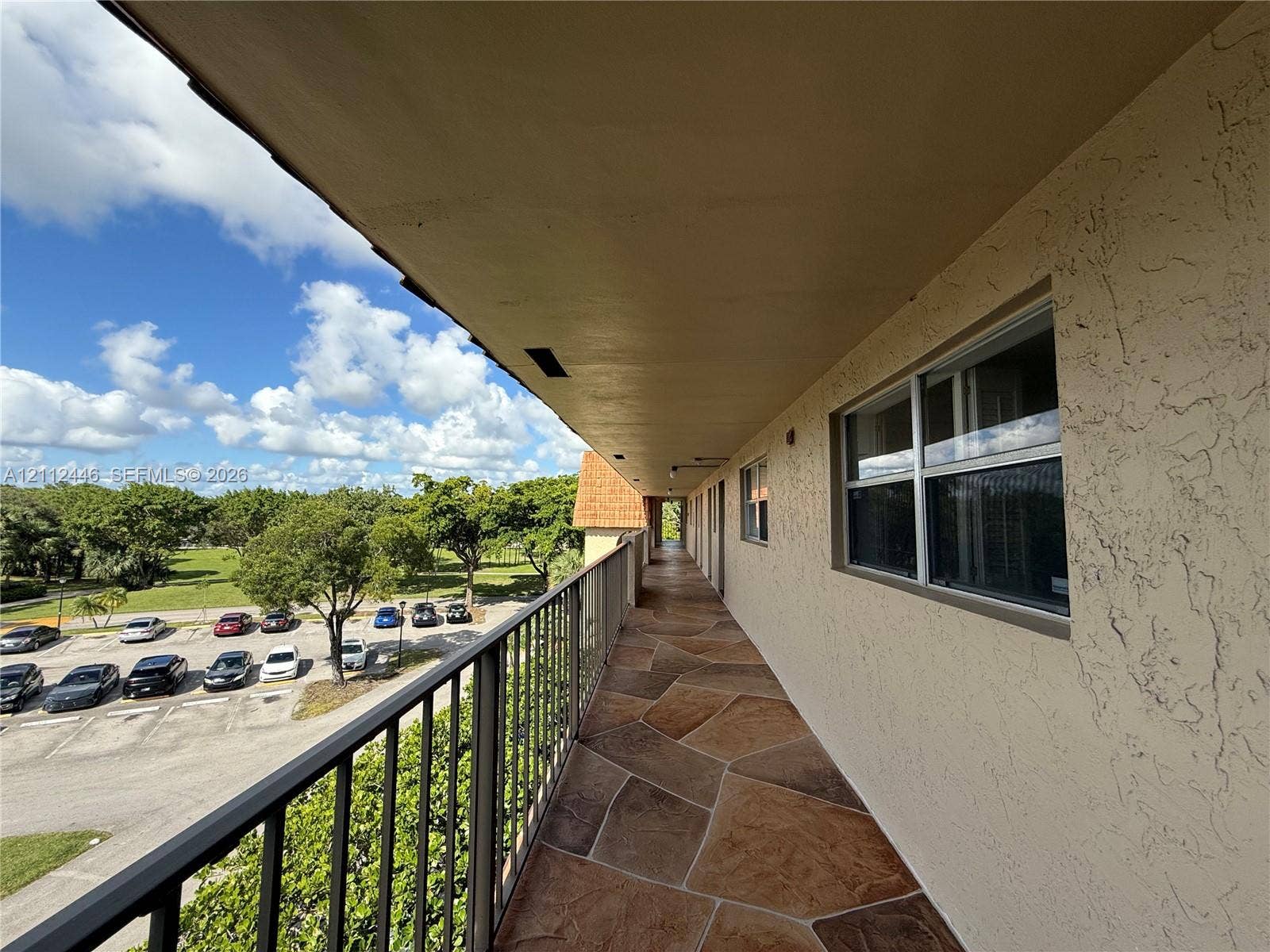 6100 S Falls Cir Drive, #411, Lauderhill, FL 33319 Exterior walkway featuring flagstone-style flooring, a metal railing, and stucco wall finishes