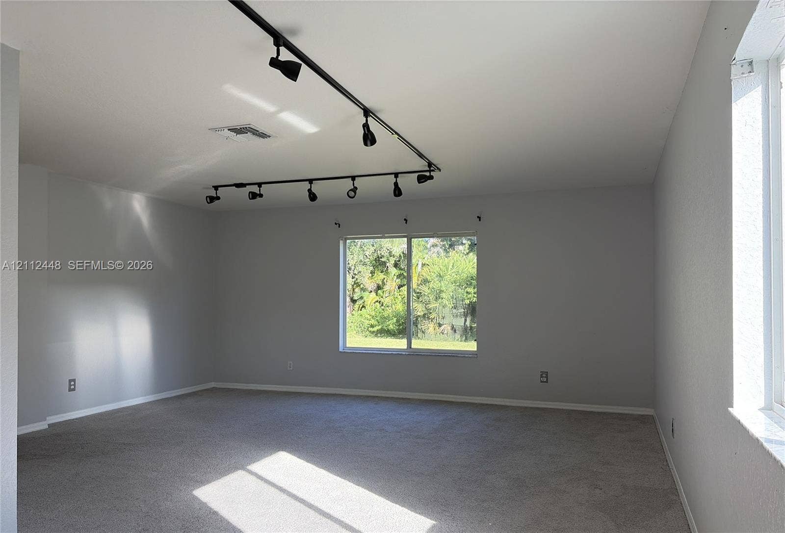 2007 SW Marblehead Way, Port St Lucie, FL 34953 Interior space featuring wall-to-wall carpeting, neutral-toned walls, and black industrial-style track lighting