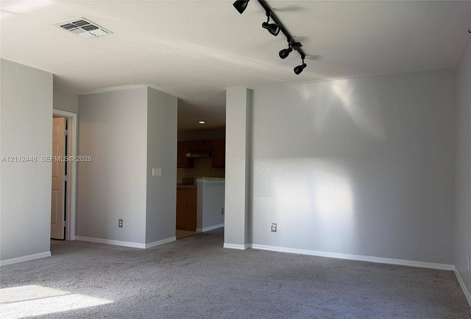 2007 SW Marblehead Way, Port St Lucie, FL 34953 Neutral-toned interior space featuring light-colored wall paint, carpeted flooring, and a multi-head adjustable track lighting fixture