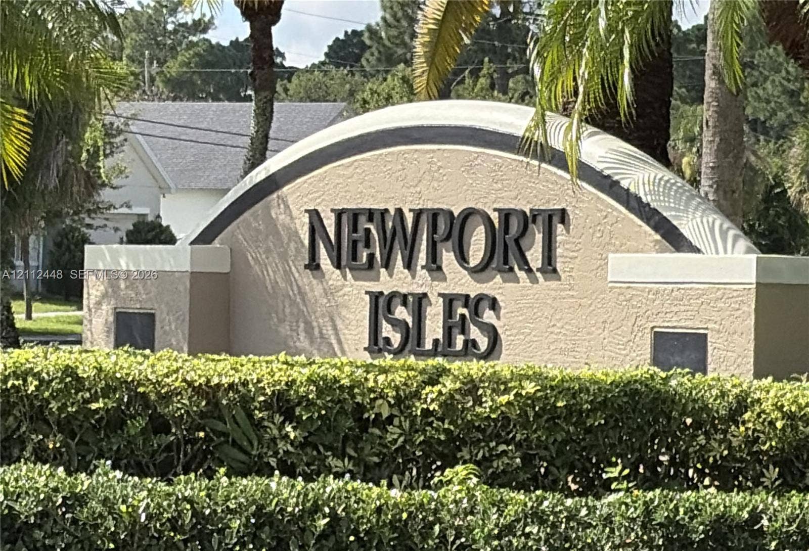 2007 SW Marblehead Way, Port St Lucie, FL 34953 Community monument sign featuring stucco construction, arched detailing, and elevated lettering, accented by mature perimeter hedging and palm trees