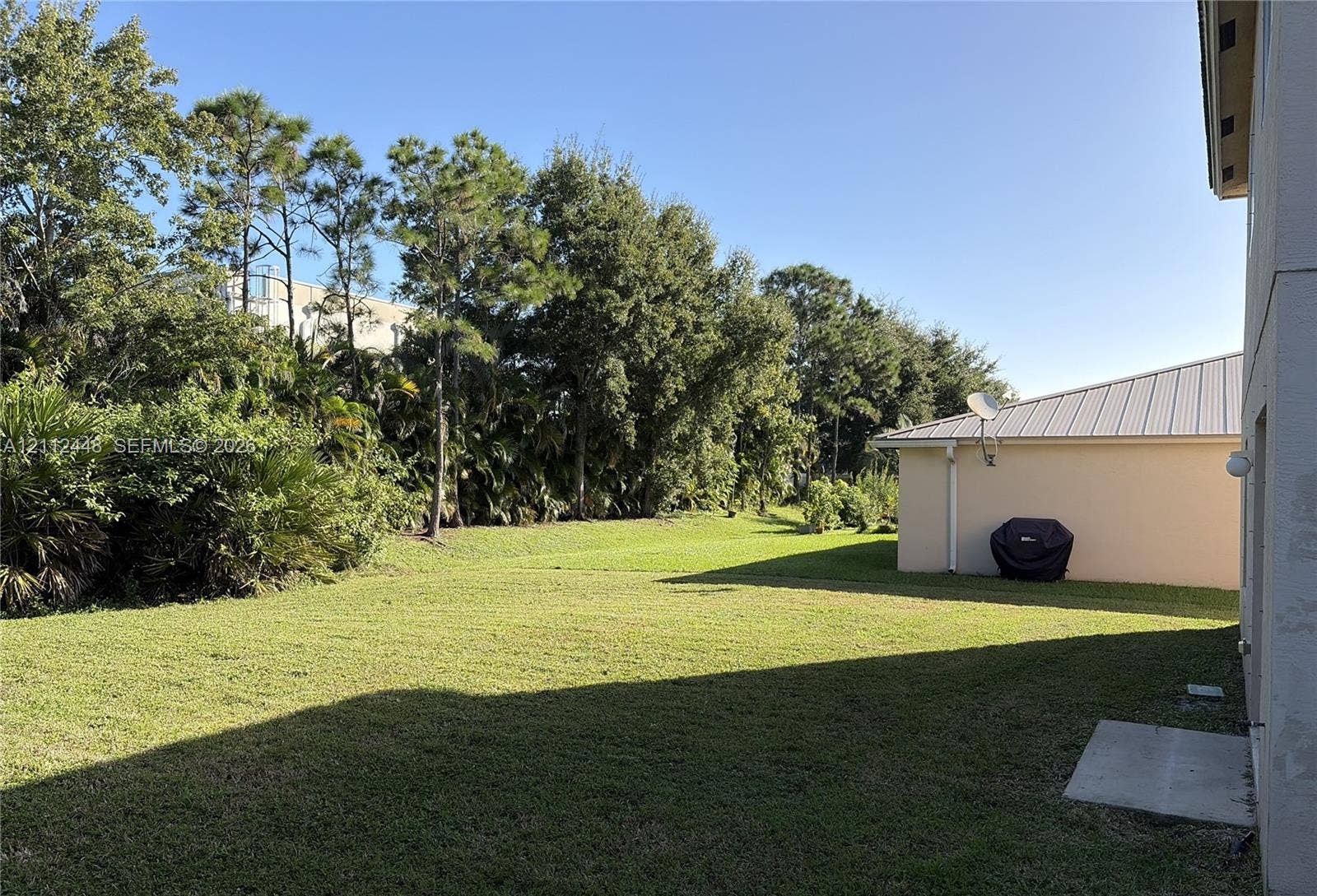 2007 SW Marblehead Way, Port St Lucie, FL 34953 Expansive backyard featuring a large grass lawn, mature trees, and landscaping border
