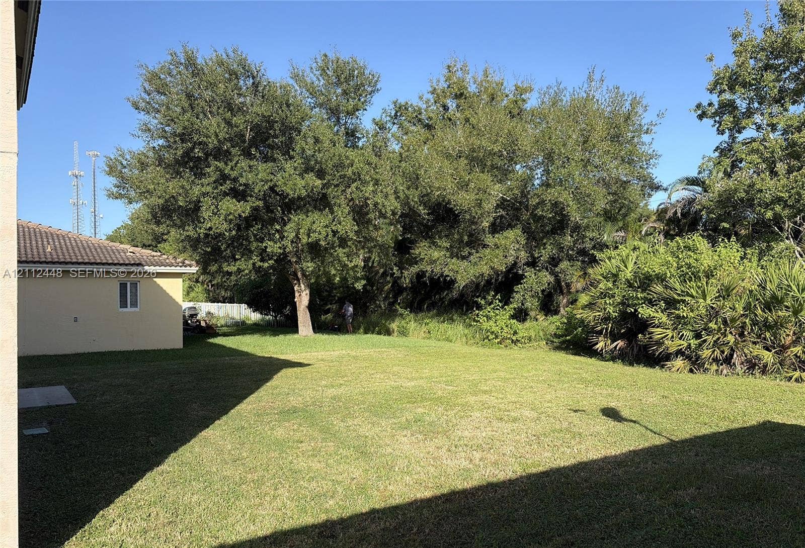 2007 SW Marblehead Way, Port St Lucie, FL 34953 Expansive backyard featuring a level lawn, mature trees, dense perimeter vegetation, and concrete exterior siding