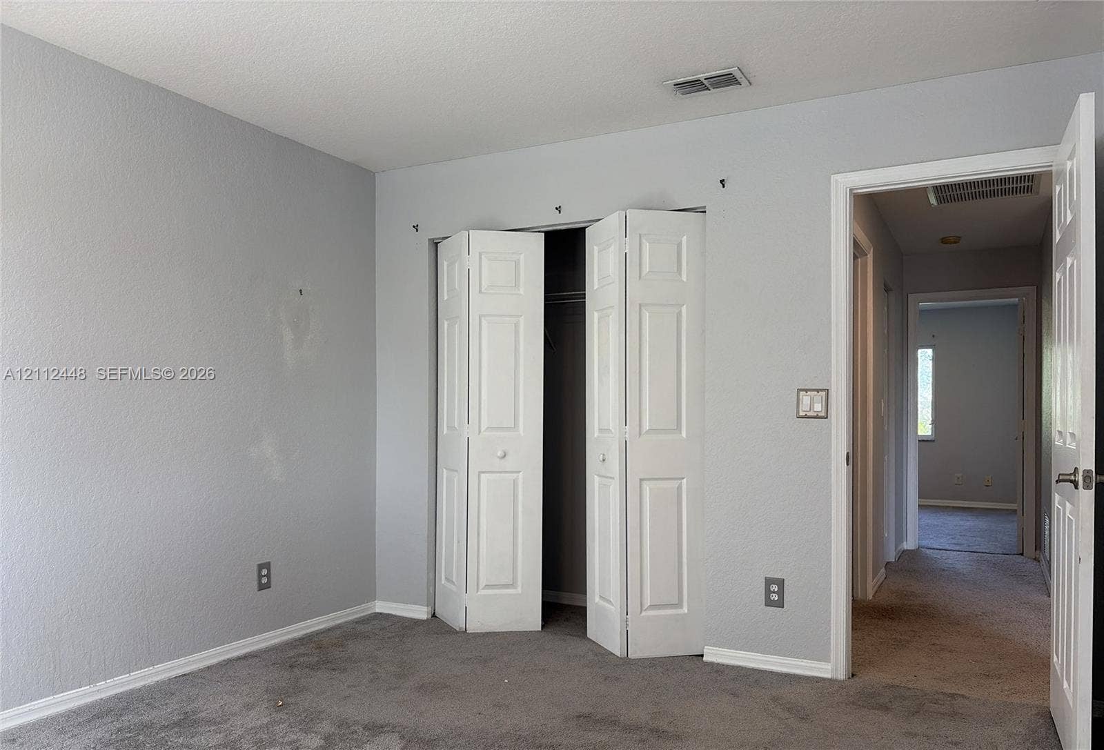 2007 SW Marblehead Way, Port St Lucie, FL 34953 Neutral-toned interior space featuring light grey walls, carpeted flooring, and a white six-panel bifold closet door
