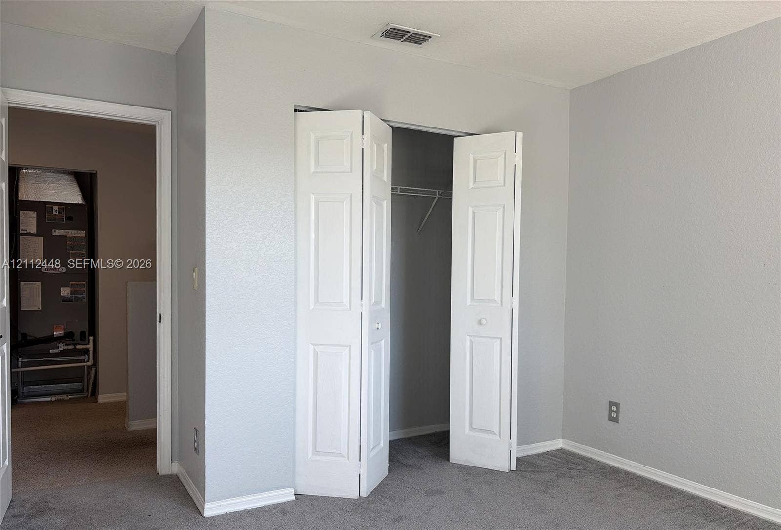 2007 SW Marblehead Way, Port St Lucie, FL 34953 Neutral-toned walls paired with gray carpeting and a closet featuring white paneled bifold doors and built-in shelving