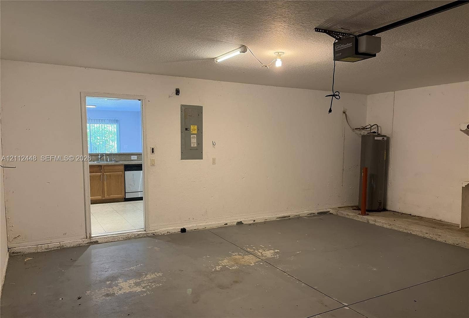 2007 SW Marblehead Way, Port St Lucie, FL 34953 Enclosed garage space featuring a concrete floor, installed automatic door opener, and integrated water heater