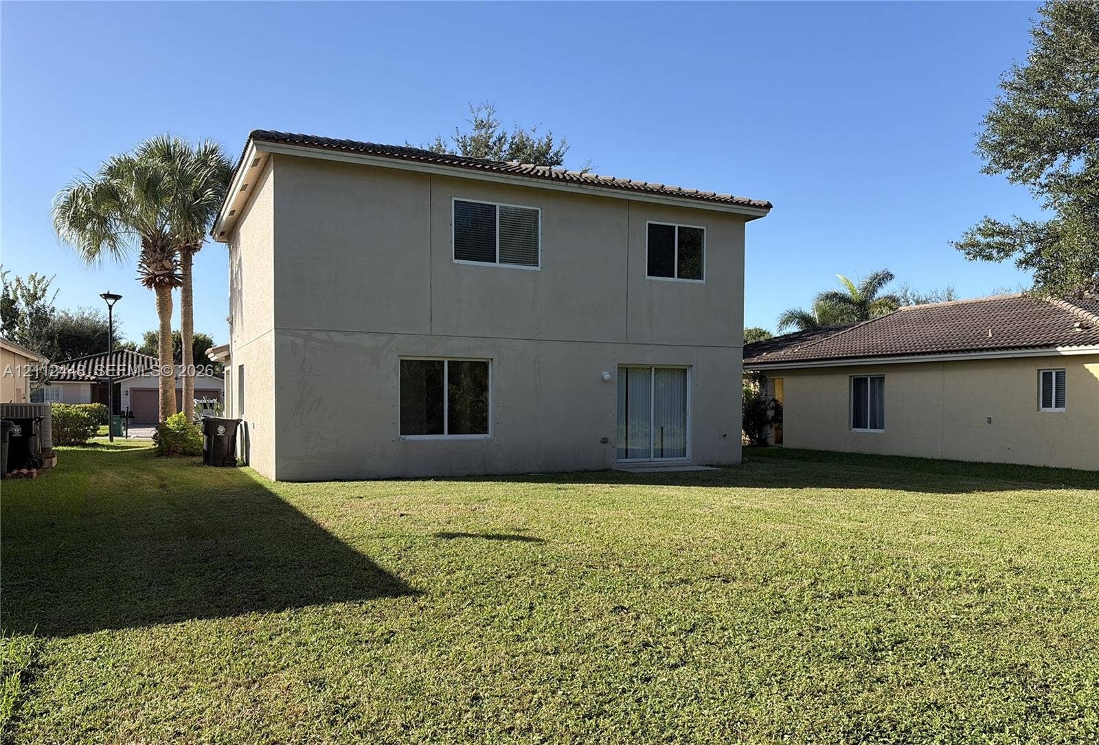 2007 SW Marblehead Way, Port St Lucie, FL 34953 Two-story exterior featuring a neutral stucco facade, tile roofing, sliding glass door, and an expansive lawn
