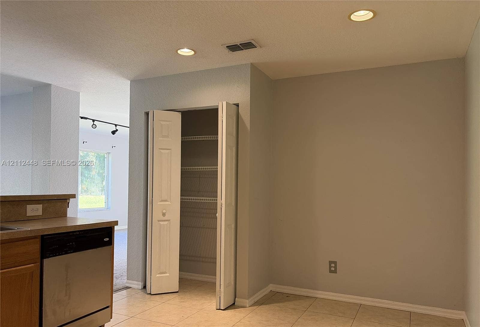 2007 SW Marblehead Way, Port St Lucie, FL 34953 Ceramic tile flooring, built-in pantry with bi-fold doors and ventilated shelving, recessed ceiling lighting, and stainless steel dishwasher