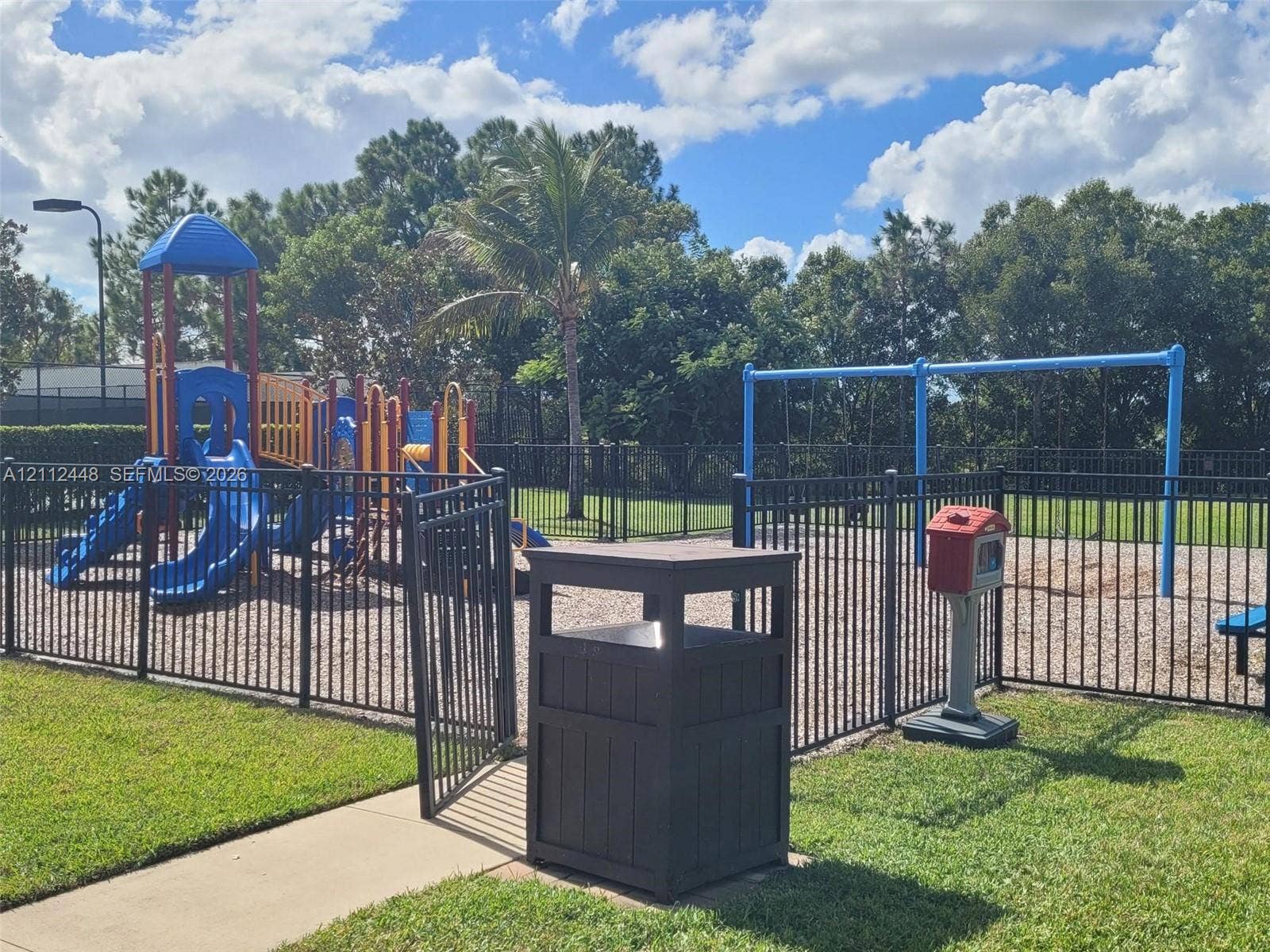 2007 SW Marblehead Way, Port St Lucie, FL 34953 Outdoor recreation area featuring a multi-component play structure, swing set, fenced perimeter, and gravel ground cover