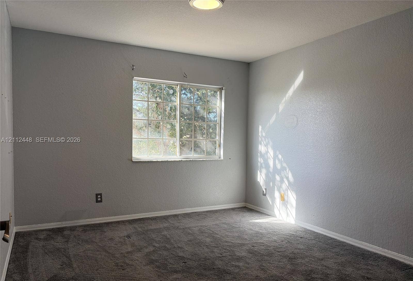 2007 SW Marblehead Way, Port St Lucie, FL 34953 Room featuring wall-to-wall carpeting, a sliding grid-pattern window, and a ceiling-mounted light fixture