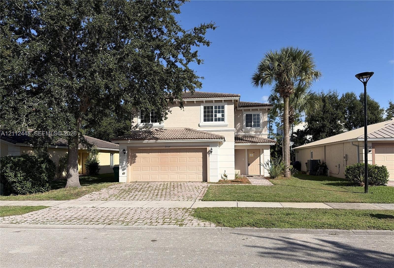 2007 SW Marblehead Way, Port St Lucie, FL 34953 Two-story stucco exterior featuring a tiled roof, an attached two-car garage, a paved driveway, and mature landscaping