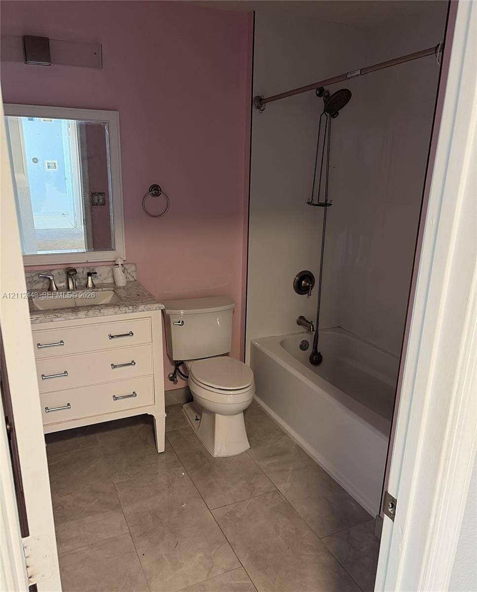 2007 SW Marblehead Way, Port St Lucie, FL 34953 Bathroom featuring a vanity with a stone-finish countertop, undermount sink, ceramic tile flooring, and a shower-tub combination with a wall-mounted fixture