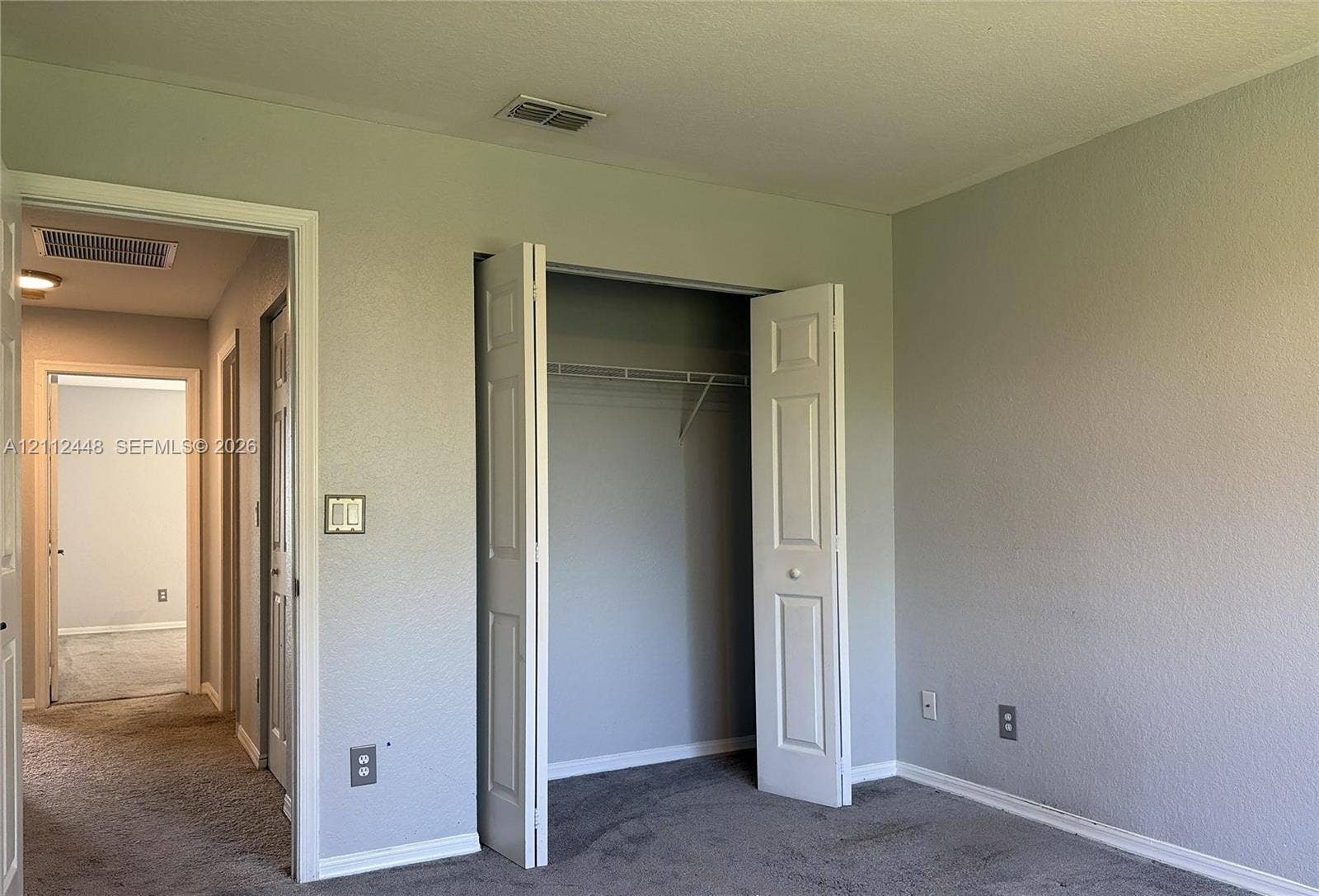 2007 SW Marblehead Way, Port St Lucie, FL 34953 Neutral-toned interior walls featuring a built-in closet with bifold doors and integrated wire shelving, complemented by carpeting