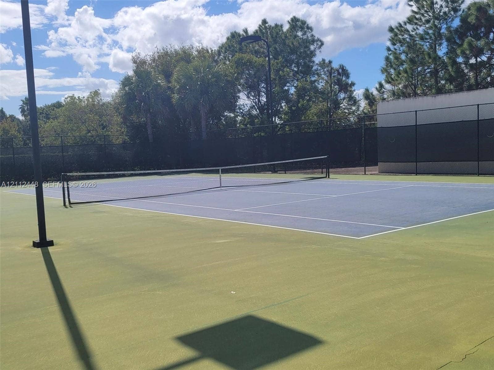 2007 SW Marblehead Way, Port St Lucie, FL 34953 Tennis court featuring a hard surface, perimeter chain-link fencing, and overhead court lighting
