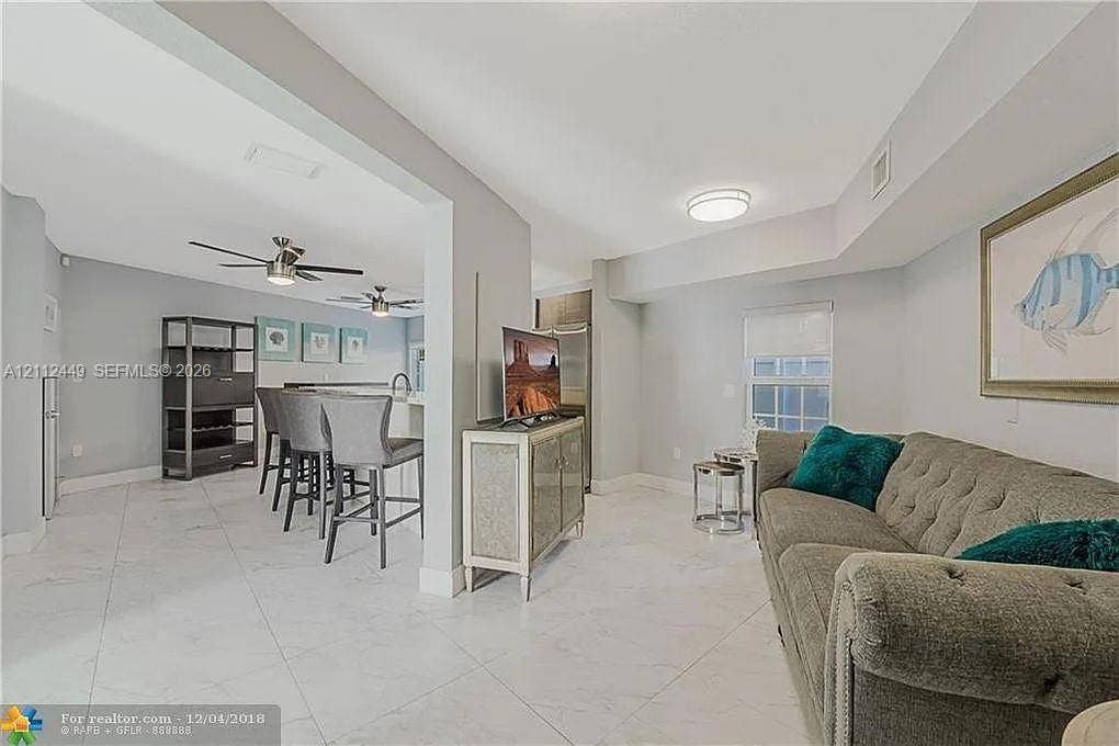 725 SE 14th Court, Fort Lauderdale, FL 33316 Open interior featuring light-colored tile flooring, flush-mount ceiling lighting, ceiling fans, and a kitchen peninsula