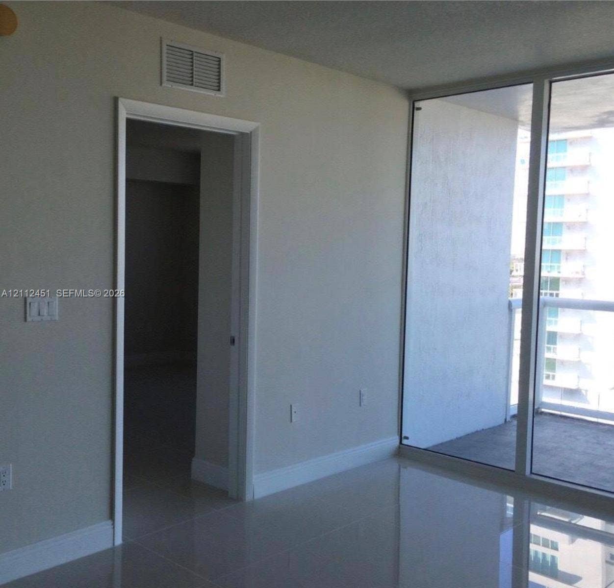 Floor-to-ceiling glass wall, polished tile flooring, and integrated balcony access