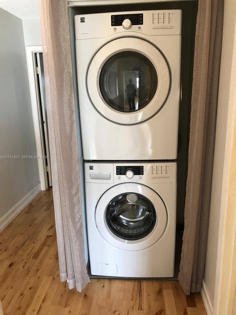 Stacked front-load washer and dryer unit set within a dedicated closet space featuring wood-finish flooring