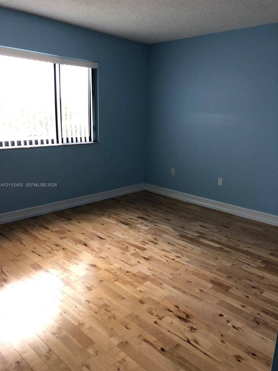 Room featuring wood-finish flooring, a large window, and light-toned wall paint