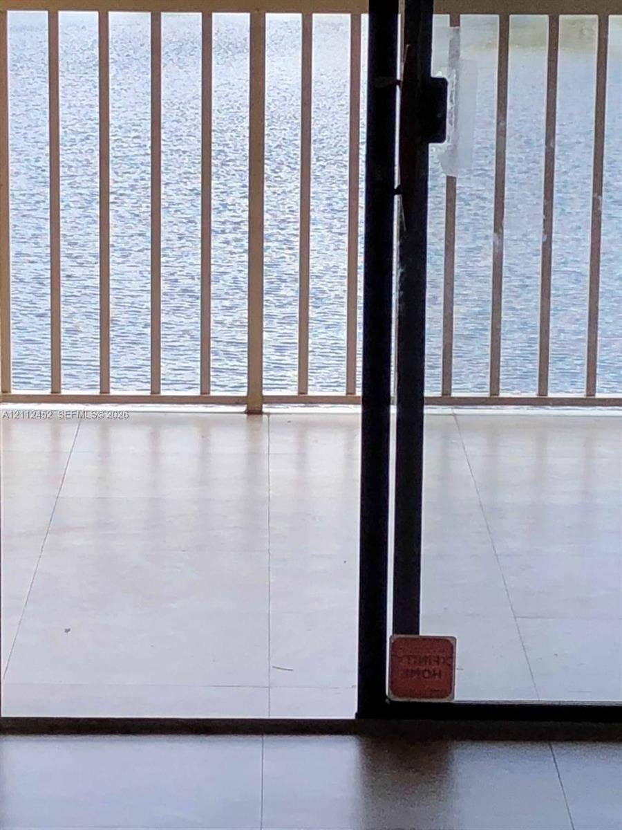 Balcony featuring light-toned tile flooring and metal railing, overlooking a body of water