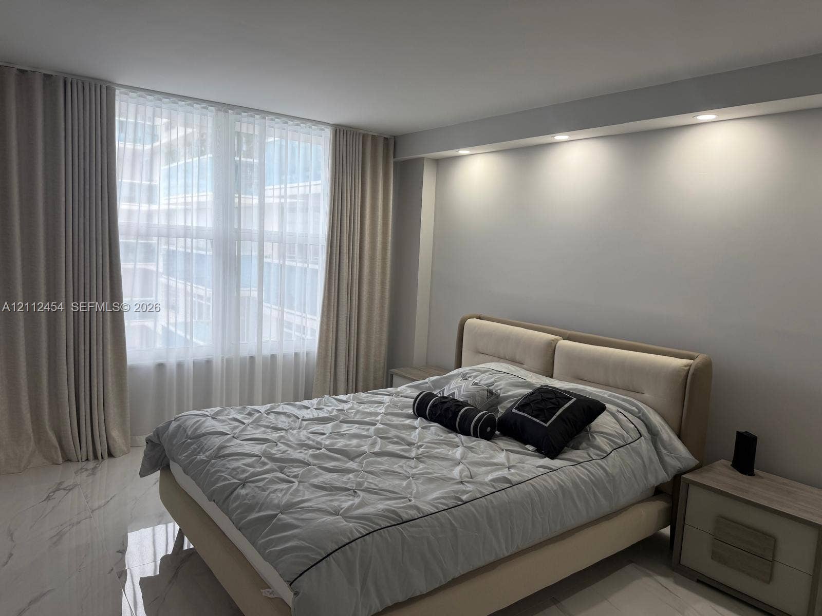 3800 S Ocean Drive, #1601, Hollywood, Hollywood, FL 33019 Floor-to-ceiling windows with layered drapery, stone-finish tile flooring, and integrated recessed ceiling lighting