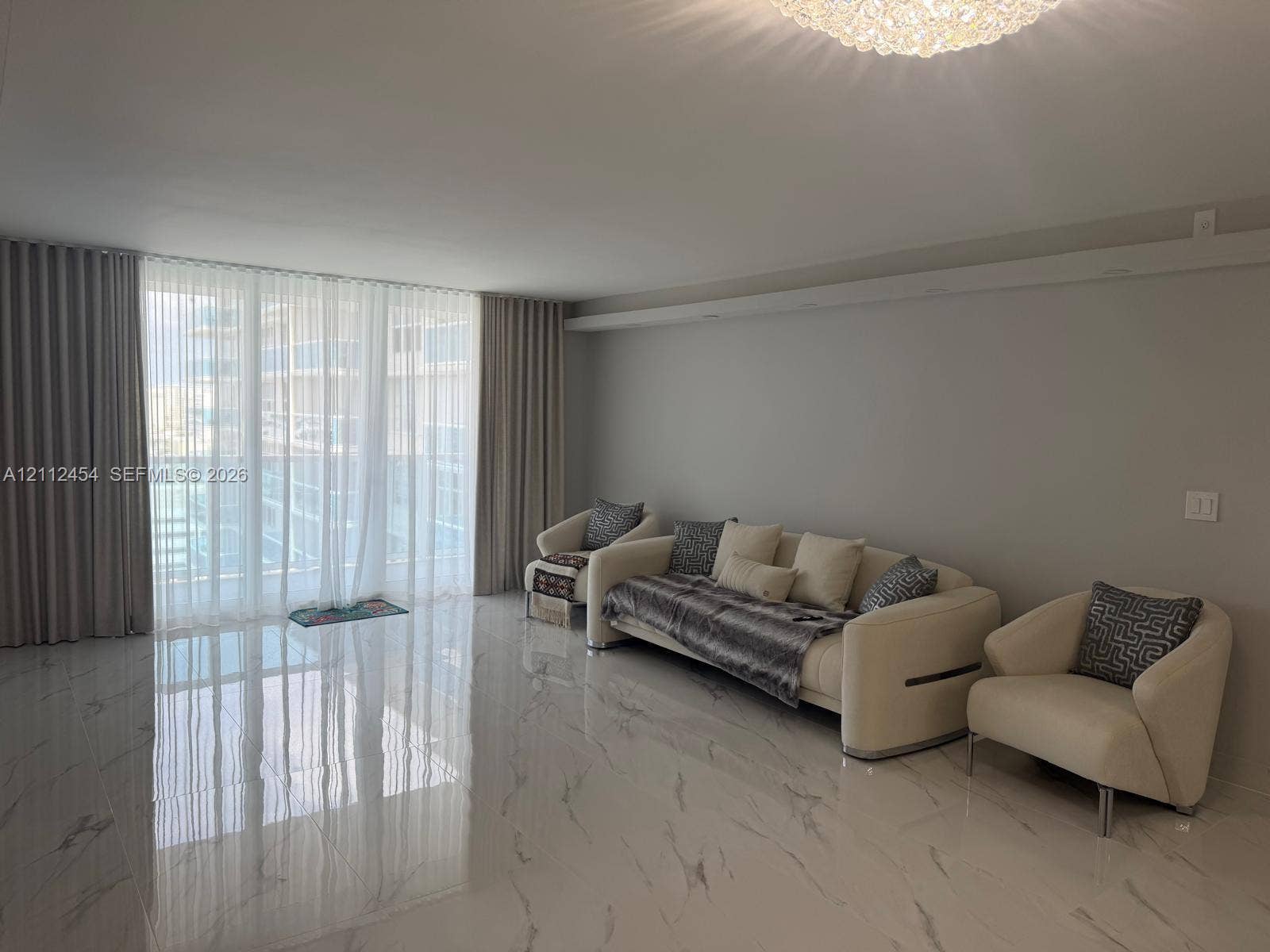 3800 S Ocean Drive, #1601, Hollywood, Hollywood, FL 33019 Polished stone-finish flooring, floor-to-ceiling drapery, and a recessed ceiling feature with a central tiered light fixture