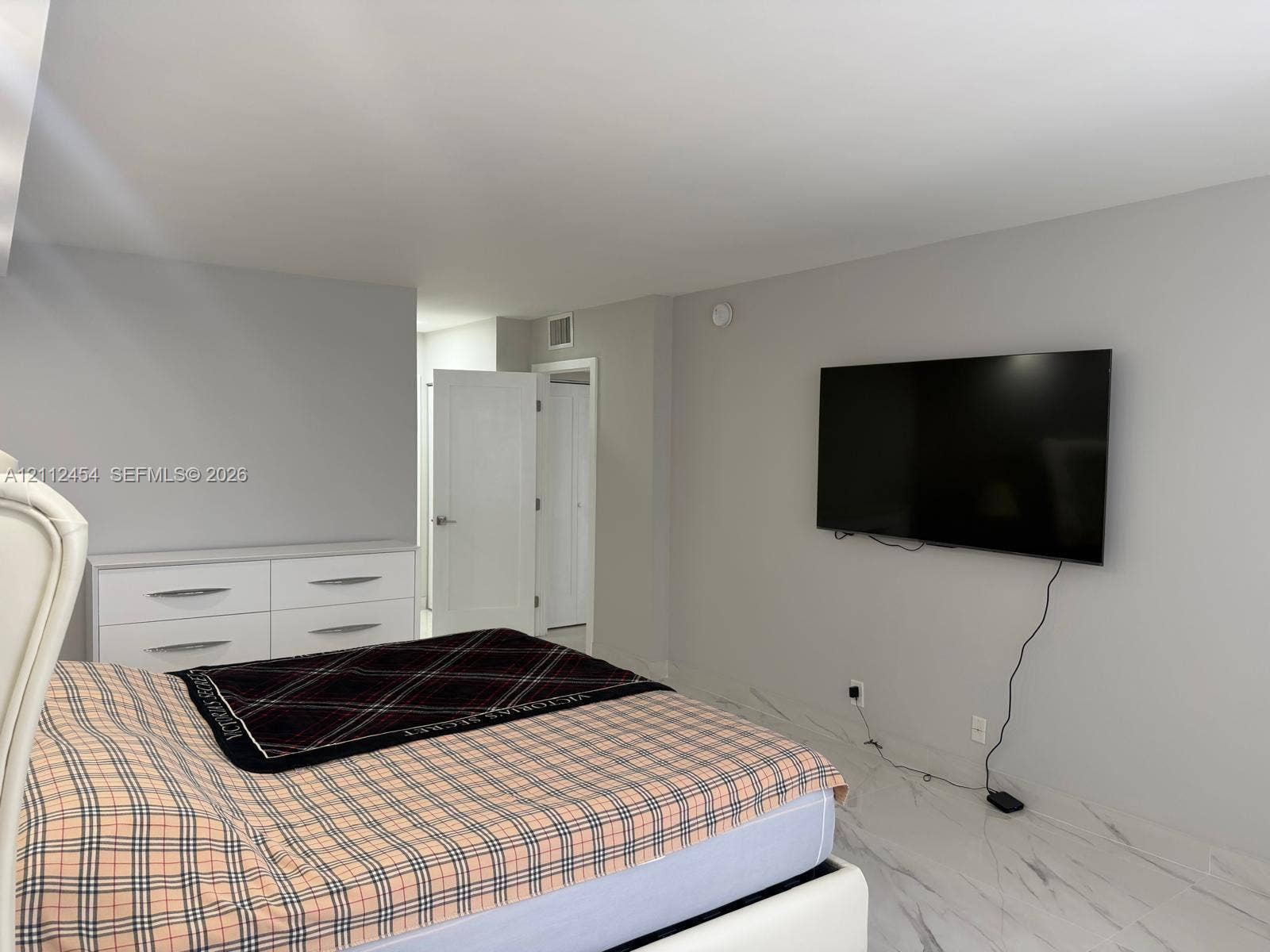 3800 S Ocean Drive, #1601, Hollywood, Hollywood, FL 33019 Neutral-toned interior space featuring light-colored stone-finish flooring and a white shaker-style door with polished chrome hardware