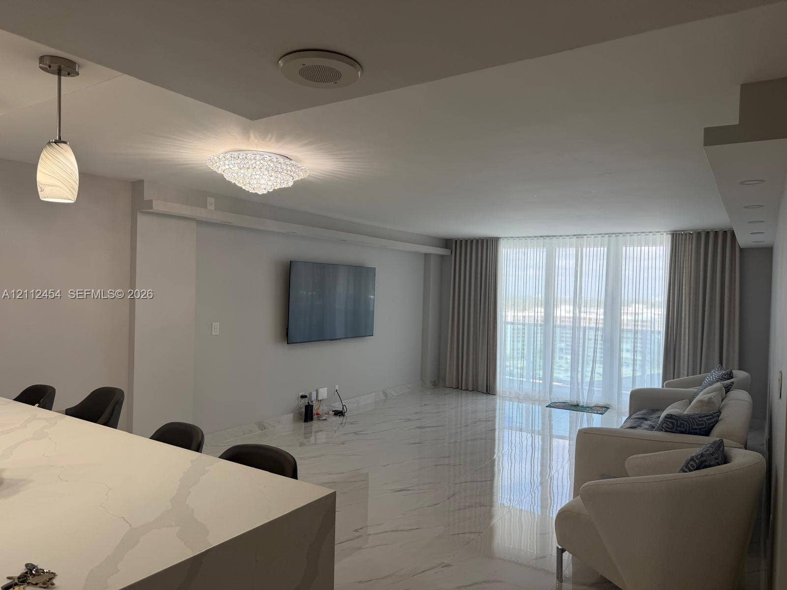 3800 S Ocean Drive, #1601, Hollywood, Hollywood, FL 33019 Polished stone-finish flooring throughout, quartz waterfall kitchen island, crystal-accent flush mount ceiling fixture, pendant lighting, and floor-to-ceiling glass wall