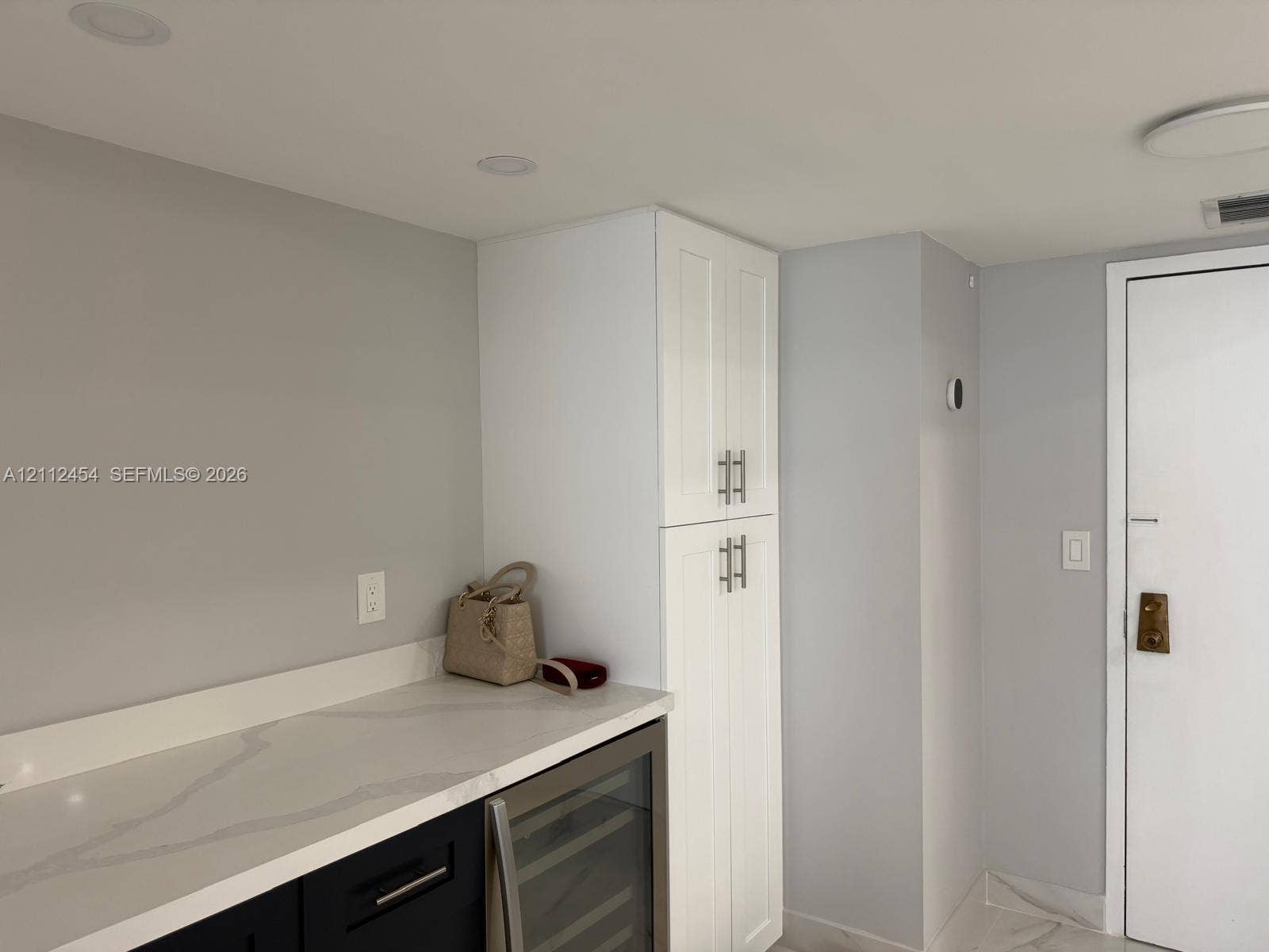 3800 S Ocean Drive, #1601, Hollywood, Hollywood, FL 33019 Custom cabinetry featuring white shaker-style pantry storage, black lower cabinets, stone-finish countertops, and an integrated wine refrigerator