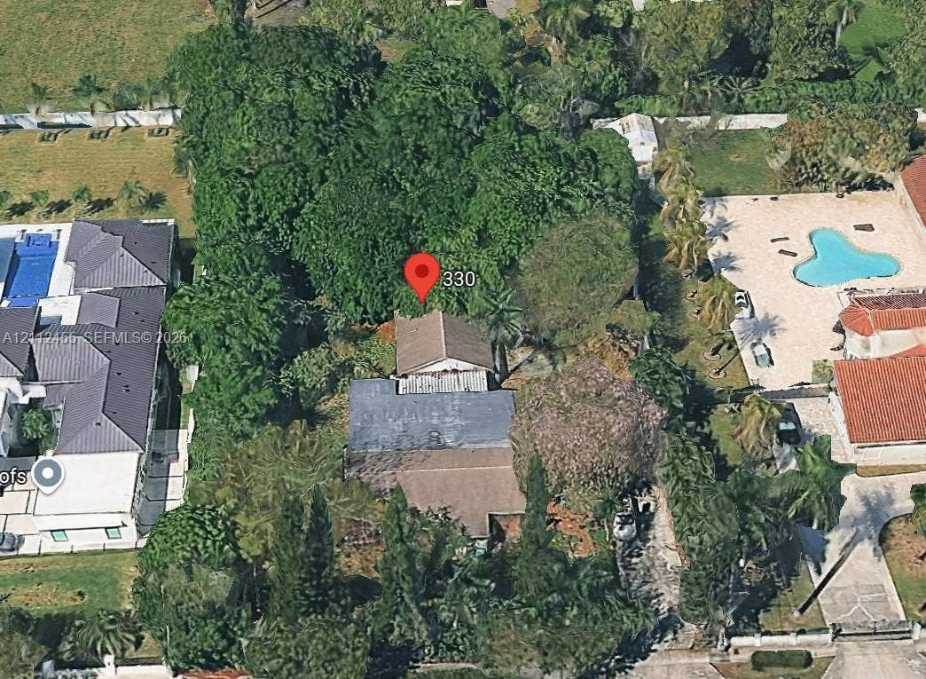 Aerial perspective showcasing a parcel with mature canopy trees, dense perimeter vegetation, and a multi-section roofline