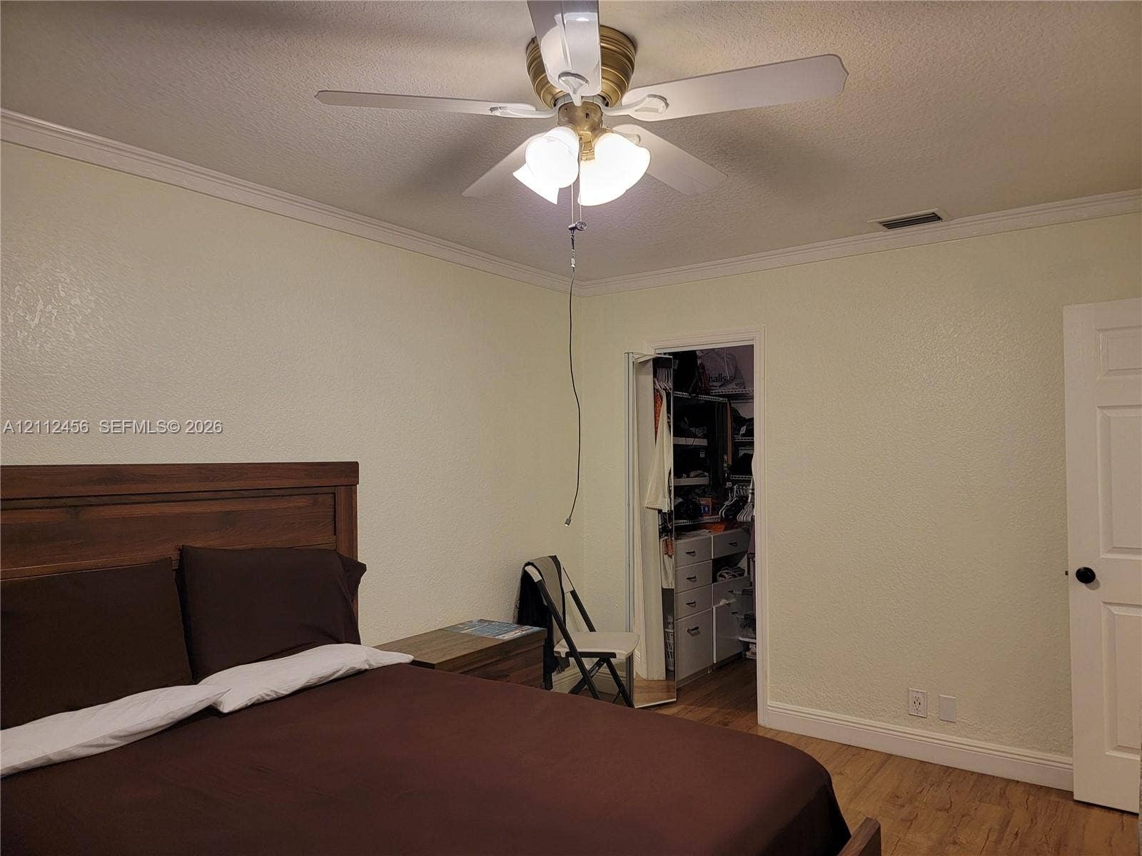 3961 NW 110th Avenue, #3961, Coral Springs, Coral Springs, FL 33065 Neutral-toned interior featuring wood-finish flooring, crown molding, a central ceiling fan with multi-light fixture, and an open walk-in closet