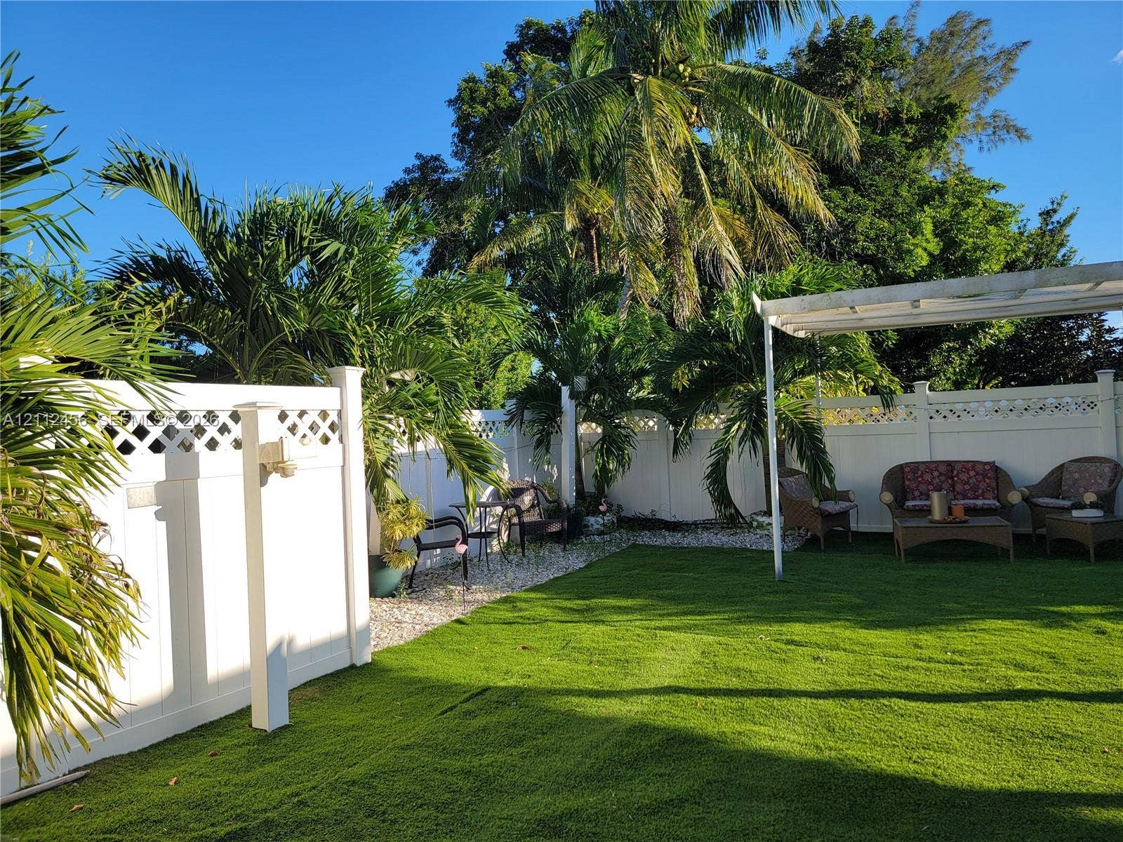 3961 NW 110th Avenue, #3961, Coral Springs, Coral Springs, FL 33065 Private backyard featuring a manicured lawn, white vinyl fencing with lattice detailing, and a detached pergola