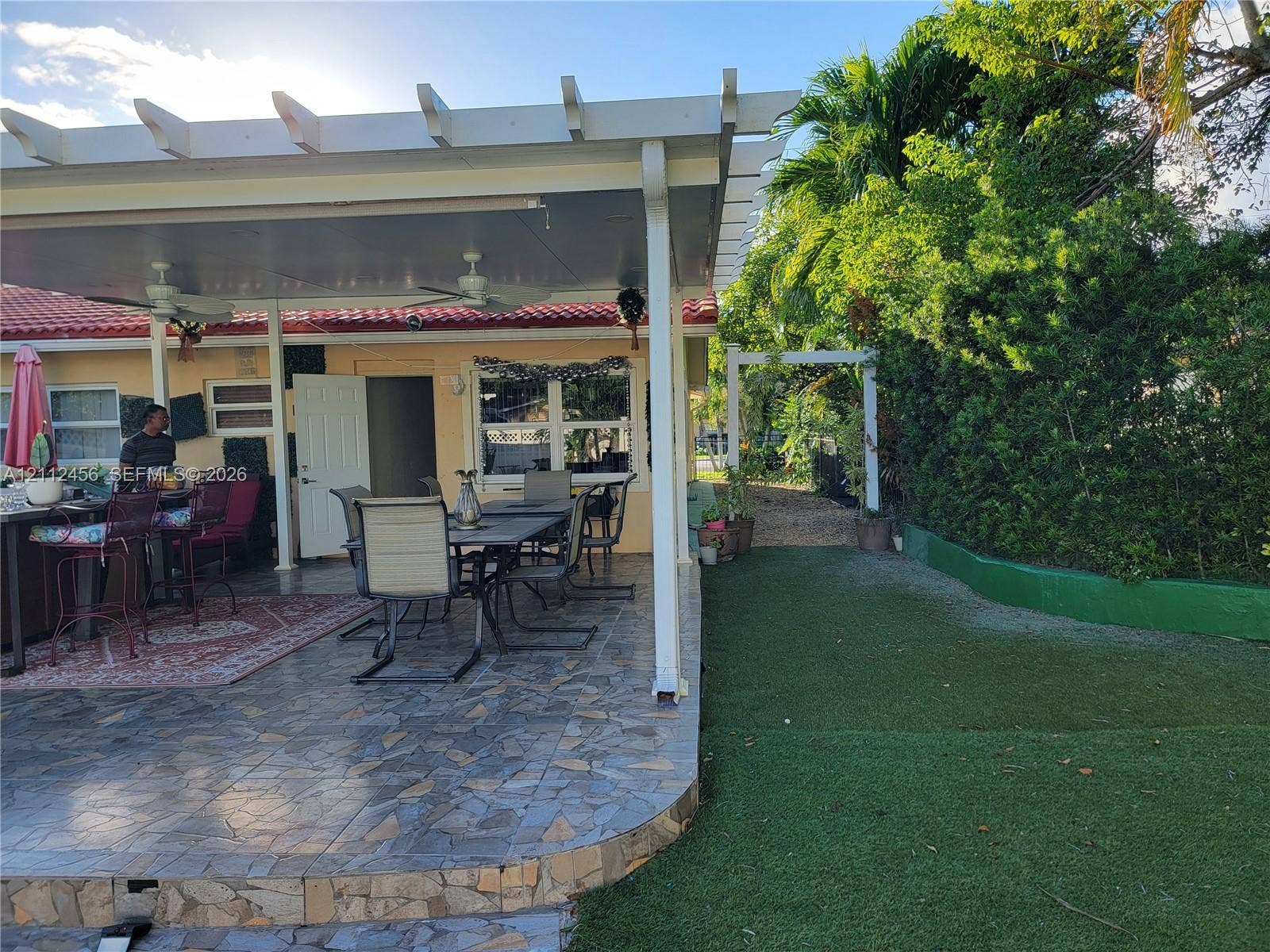 3961 NW 110th Avenue, #3961, Coral Springs, Coral Springs, FL 33065 Covered patio with a pergola extension, multi-tone tiled flooring, artificial turf lawn, and mature perimeter landscaping