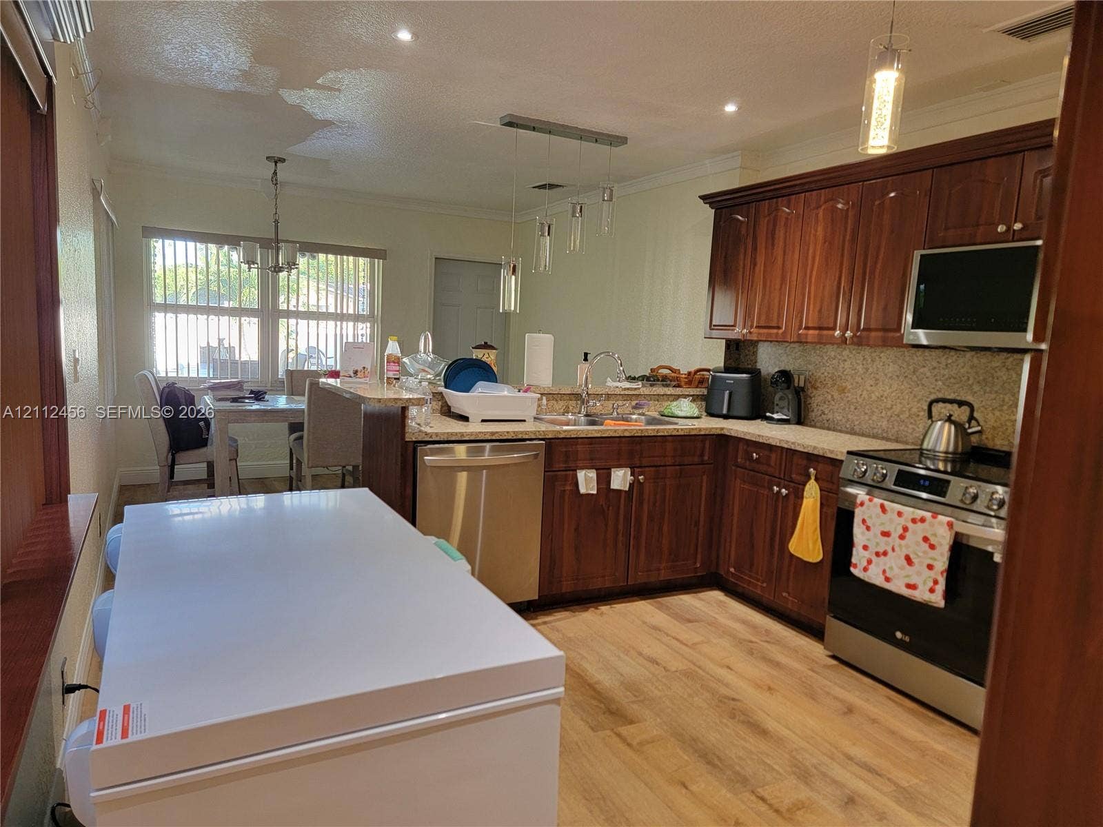 3961 NW 110th Avenue, #3961, Coral Springs, Coral Springs, FL 33065 Kitchen featuring wood-finish cabinetry, stone-texture countertops, stainless steel appliances, wood-finish flooring, and multi-pendant lighting