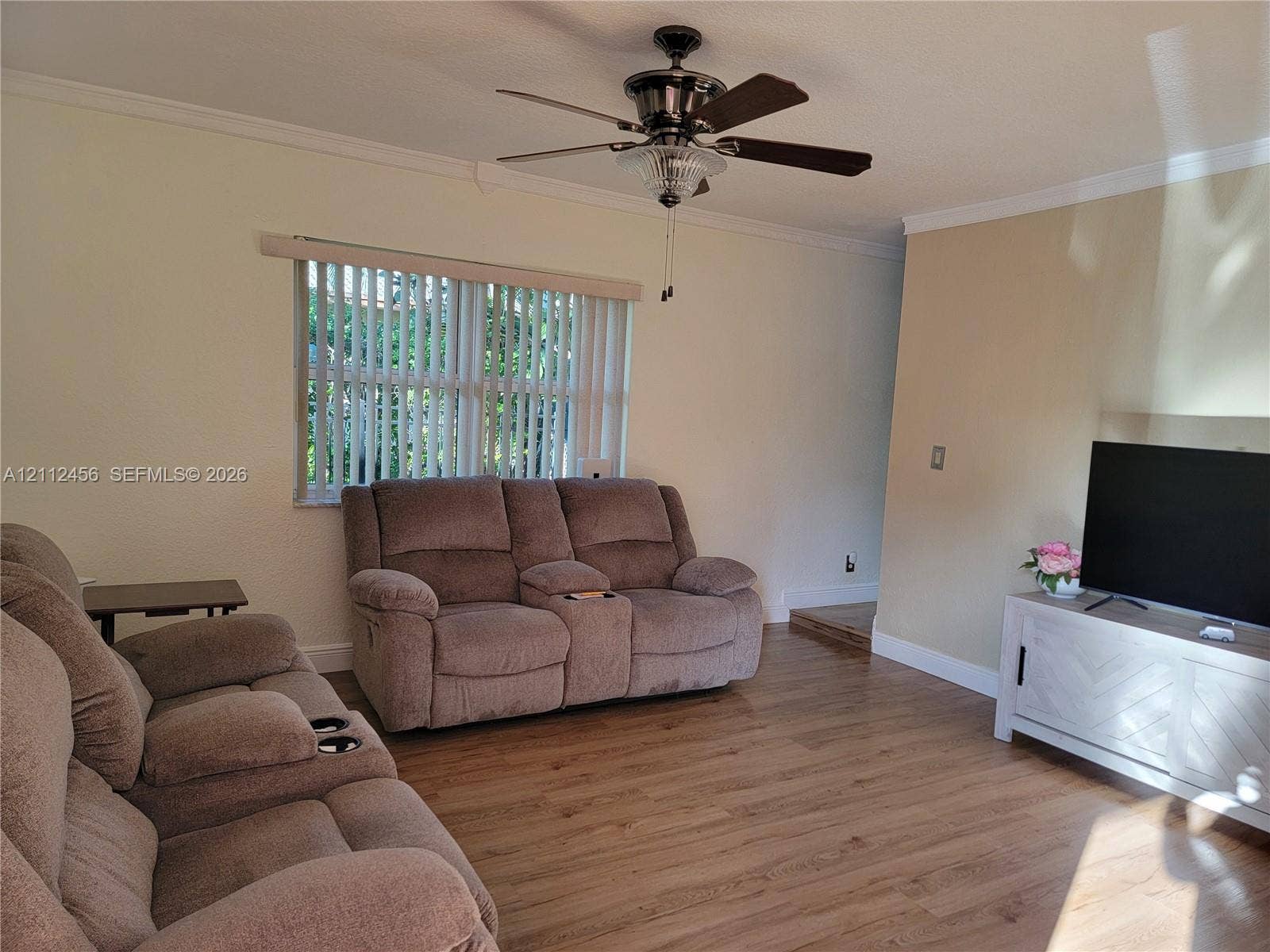 3961 NW 110th Avenue, #3961, Coral Springs, Coral Springs, FL 33065 Room featuring wood-finish flooring, crown molding, a multi-blade ceiling fan with integrated lighting, and vertical window blinds