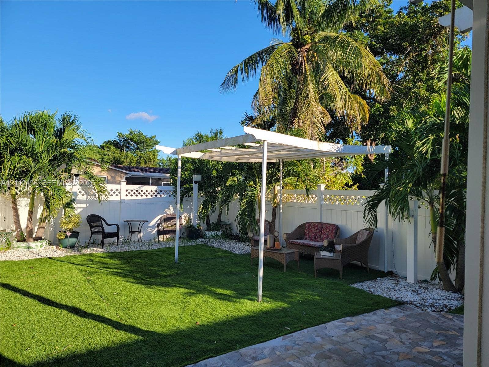 3961 NW 110th Avenue, #3961, Coral Springs, Coral Springs, FL 33065 Rear yard featuring a white lattice-top privacy fence, synthetic turf lawn, white pergola, and stone paver patio