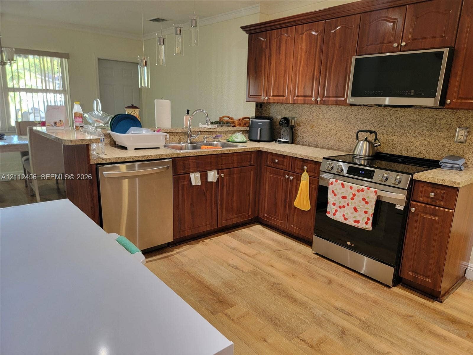 3961 NW 110th Avenue, #3961, Coral Springs, Coral Springs, FL 33065 Kitchen featuring stained wood cabinetry, stone-finish countertops, stainless steel appliances, a peninsula with a stainless steel sink, and wood-finish flooring