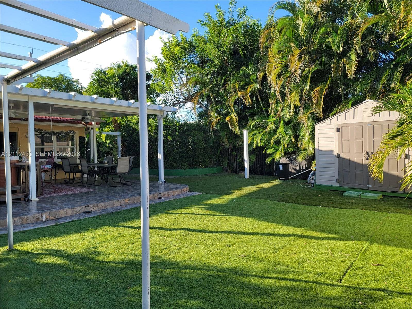 3961 NW 110th Avenue, #3961, Coral Springs, Coral Springs, FL 33065 Rear exterior space featuring a covered patio with a white pergola, a lawn area, and a detached storage shed