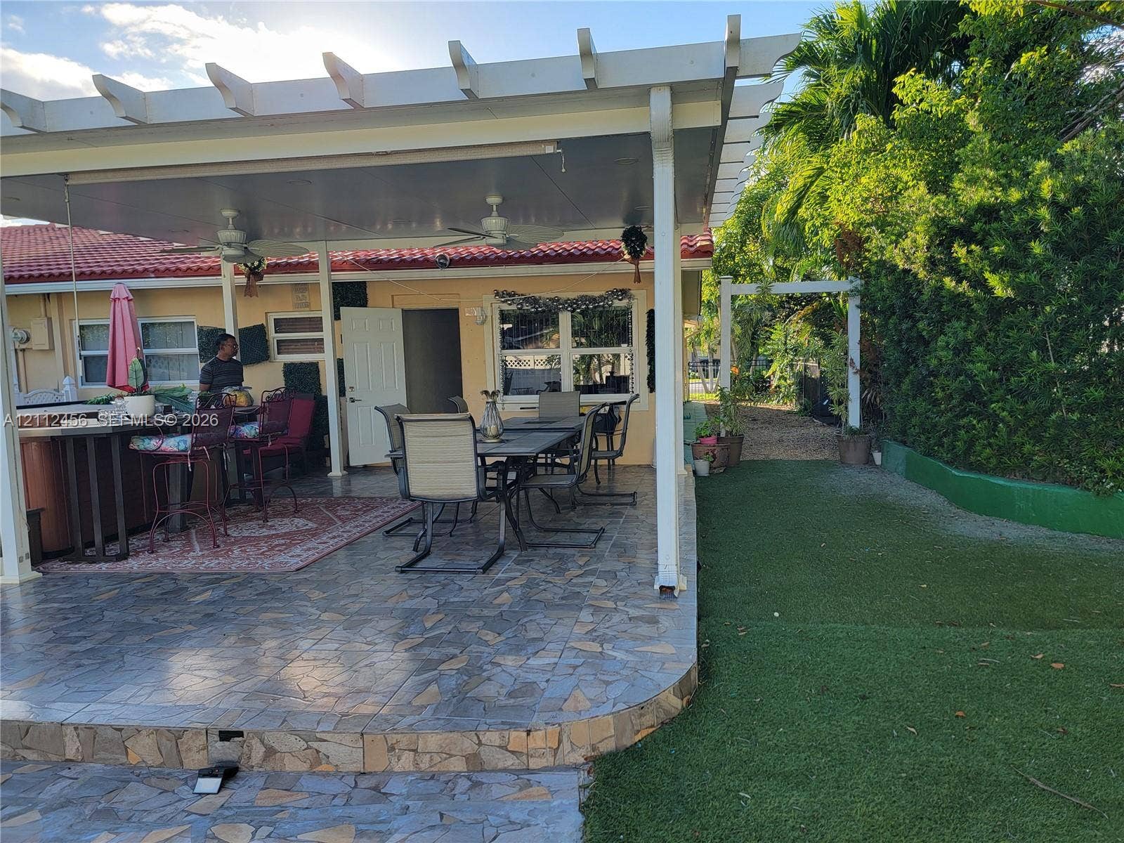 3961 NW 110th Avenue, #3961, Coral Springs, Coral Springs, FL 33065 Covered patio featuring a solid-surface roof structure, ceiling fans, stone-finish tile flooring, and a pergola perimeter