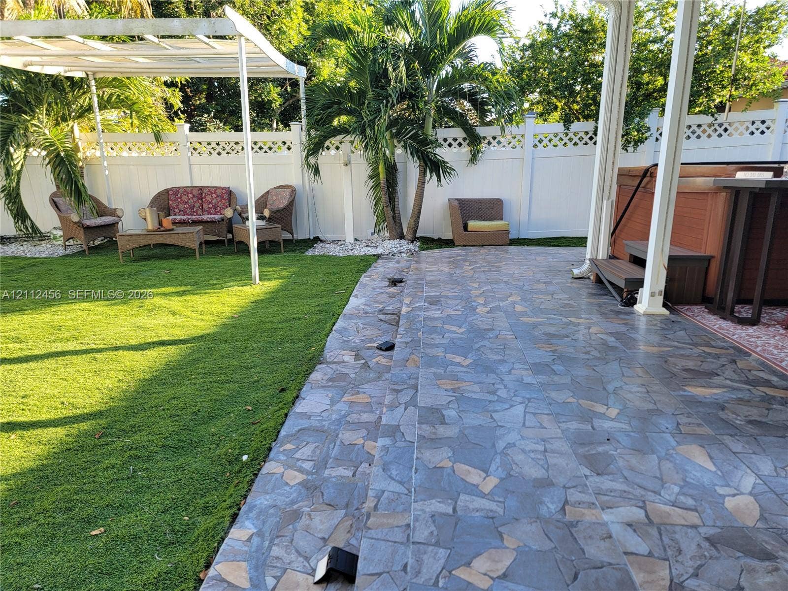 3961 NW 110th Avenue, #3961, Coral Springs, Coral Springs, FL 33065 Private backyard featuring a flagstone patio, custom white lattice-topped fencing, a built-in pergola, and an integrated hot tub
