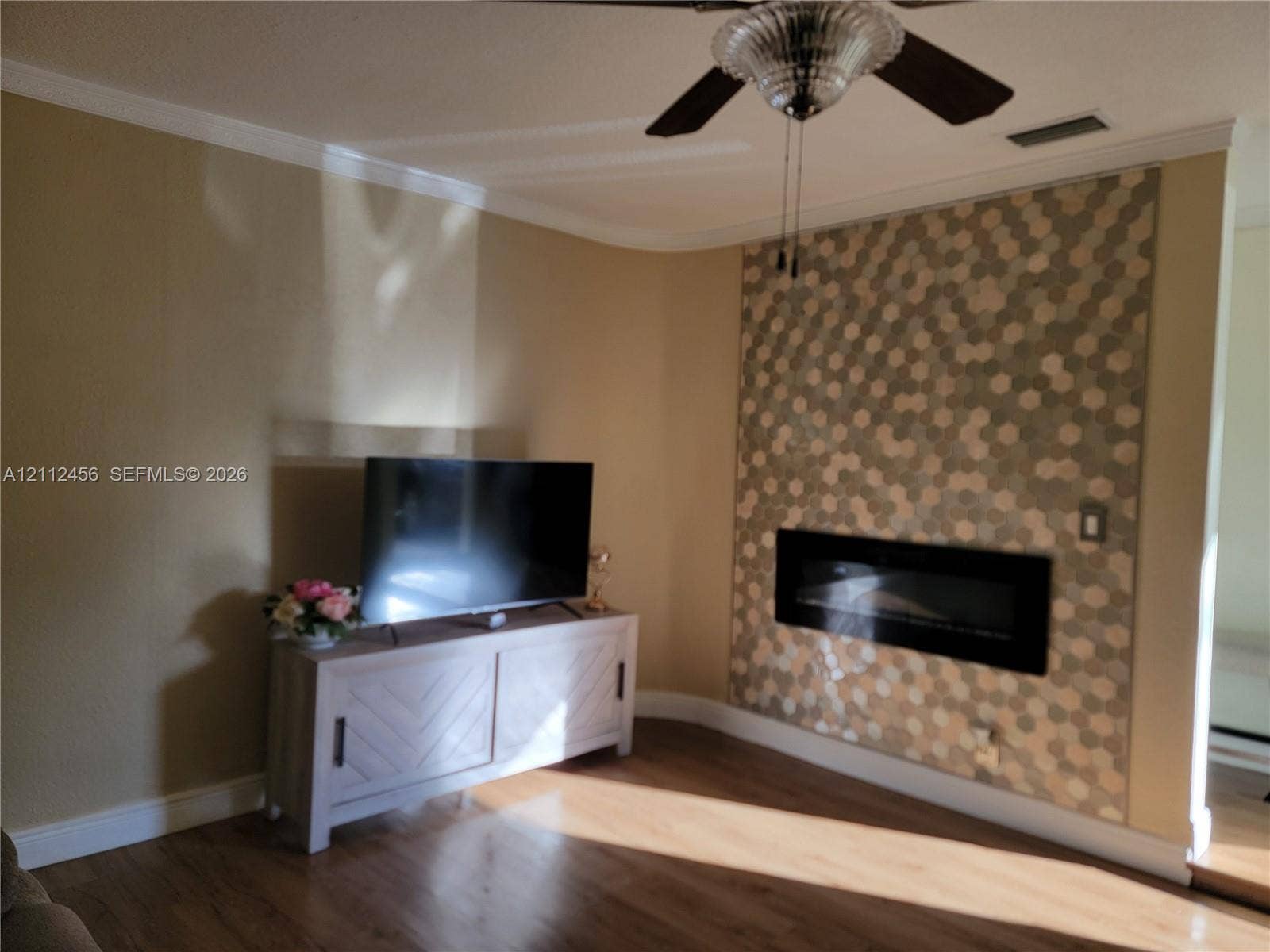 3961 NW 110th Avenue, #3961, Coral Springs, Coral Springs, FL 33065 Living area featuring wood-finish flooring, a wall-mounted electric fireplace, and a decorative hexagonal tile accent wall