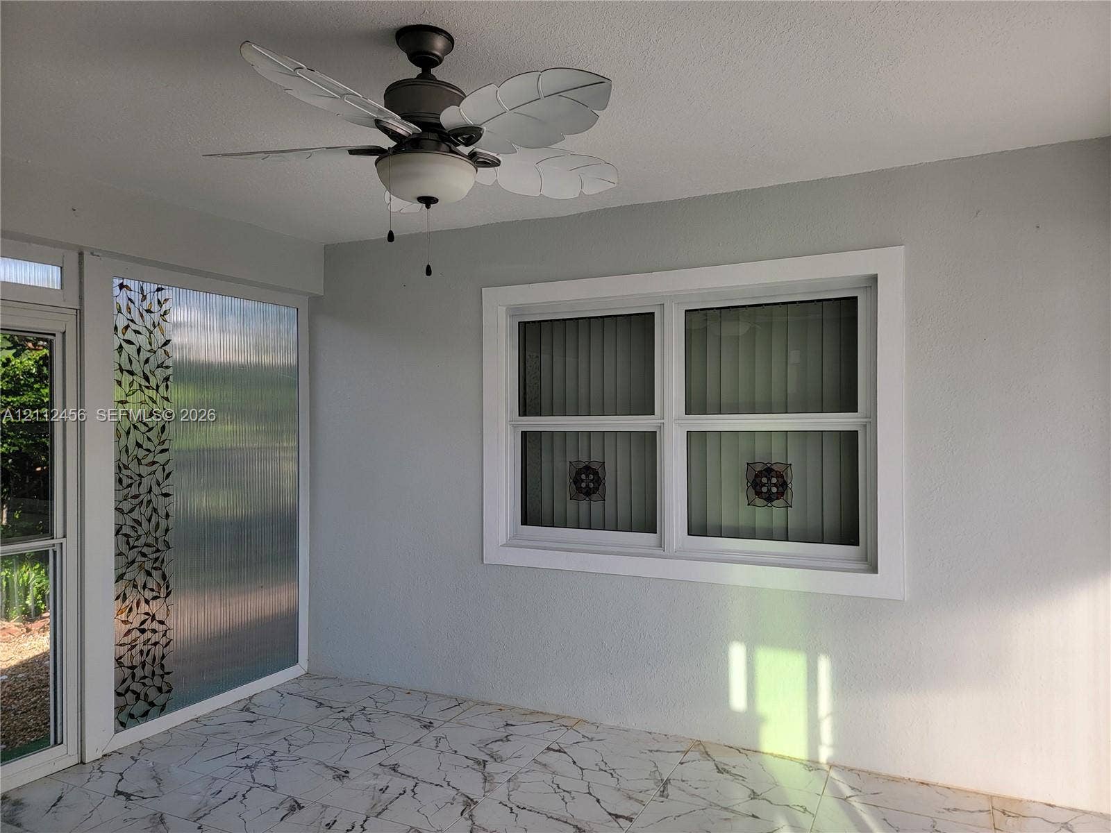 3961 NW 110th Avenue, #3961, Coral Springs, Coral Springs, FL 33065 Enclosed patio featuring patterned tile flooring, a dual-light ceiling fan with leaf-shaped blades, and decorative glass paneling