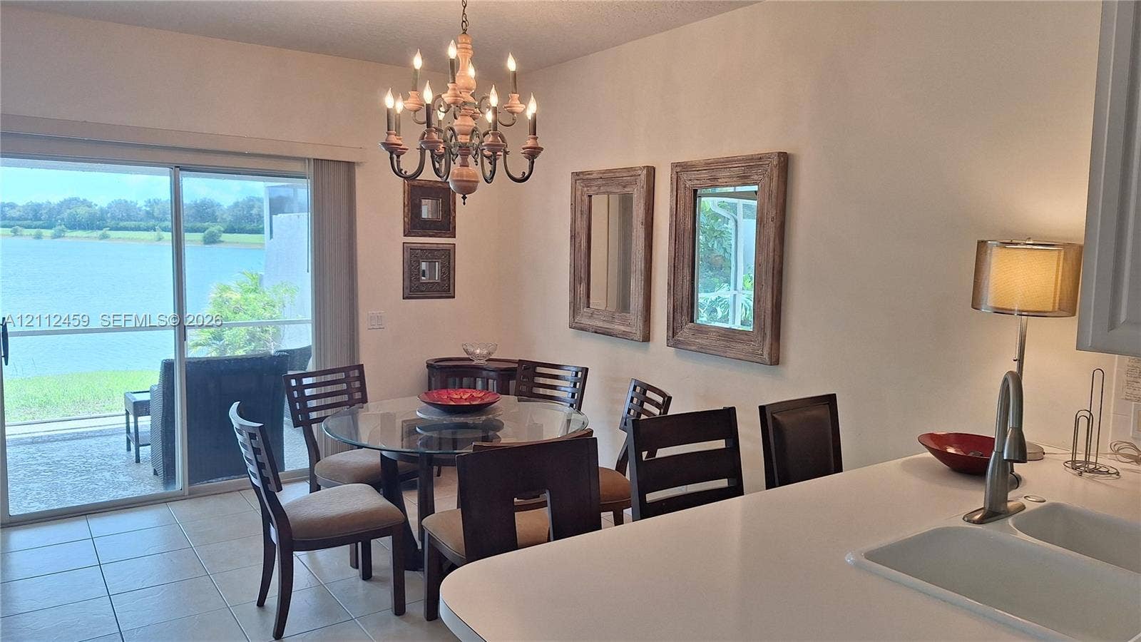 Dining area featuring tile flooring, a multi-arm chandelier, and sliding glass doors with water scenery