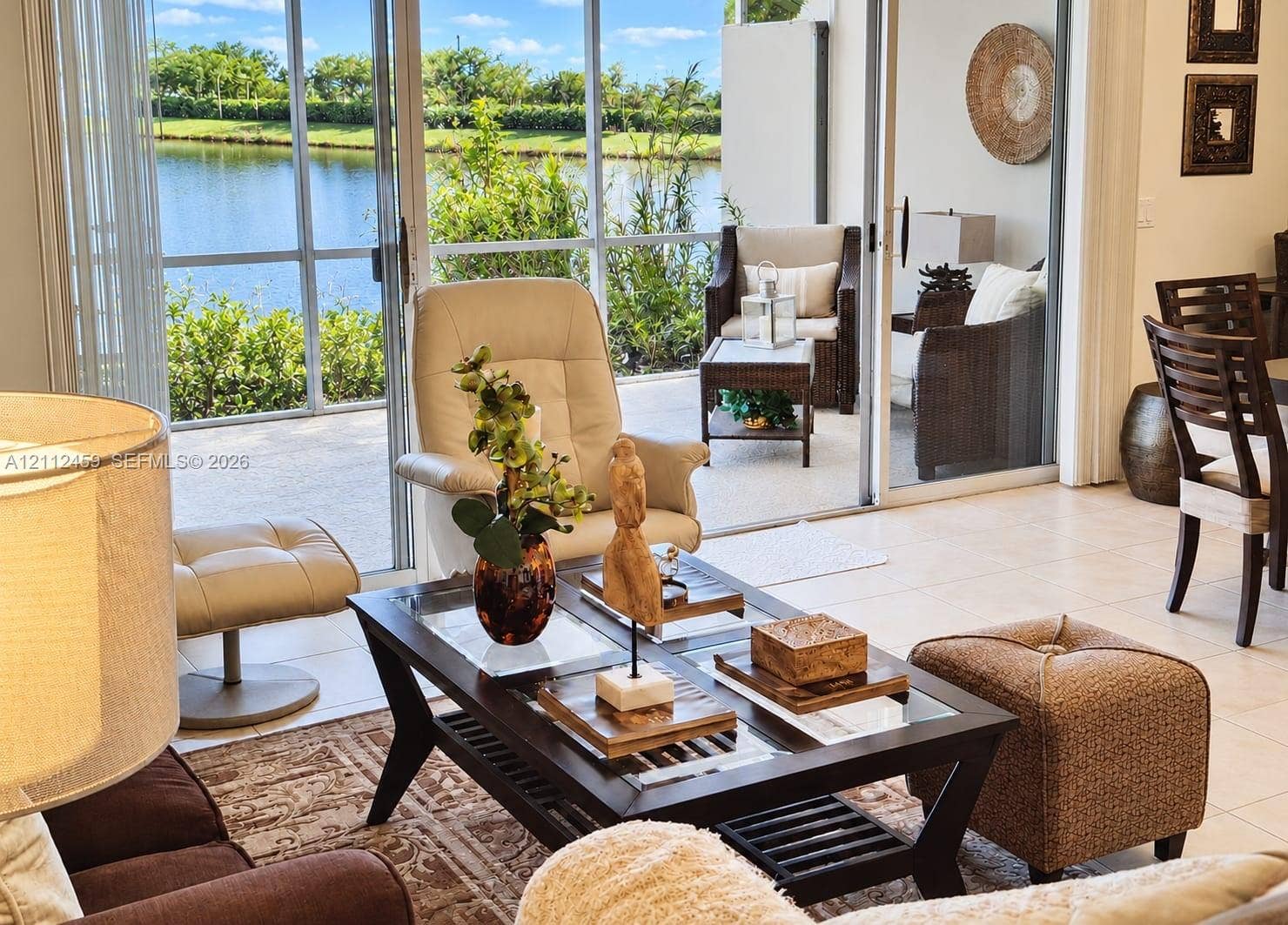 Screened-in patio with tile flooring and sliding glass door access, featuring water scenery