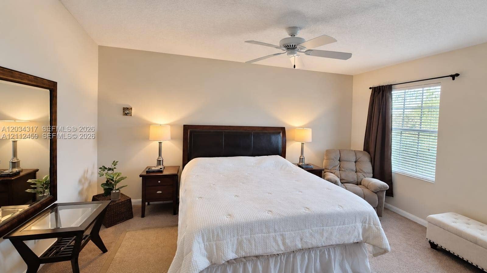 Spacious room featuring neutral wall tones, wall-to-wall carpeting, and a white ceiling fan with integrated lighting
