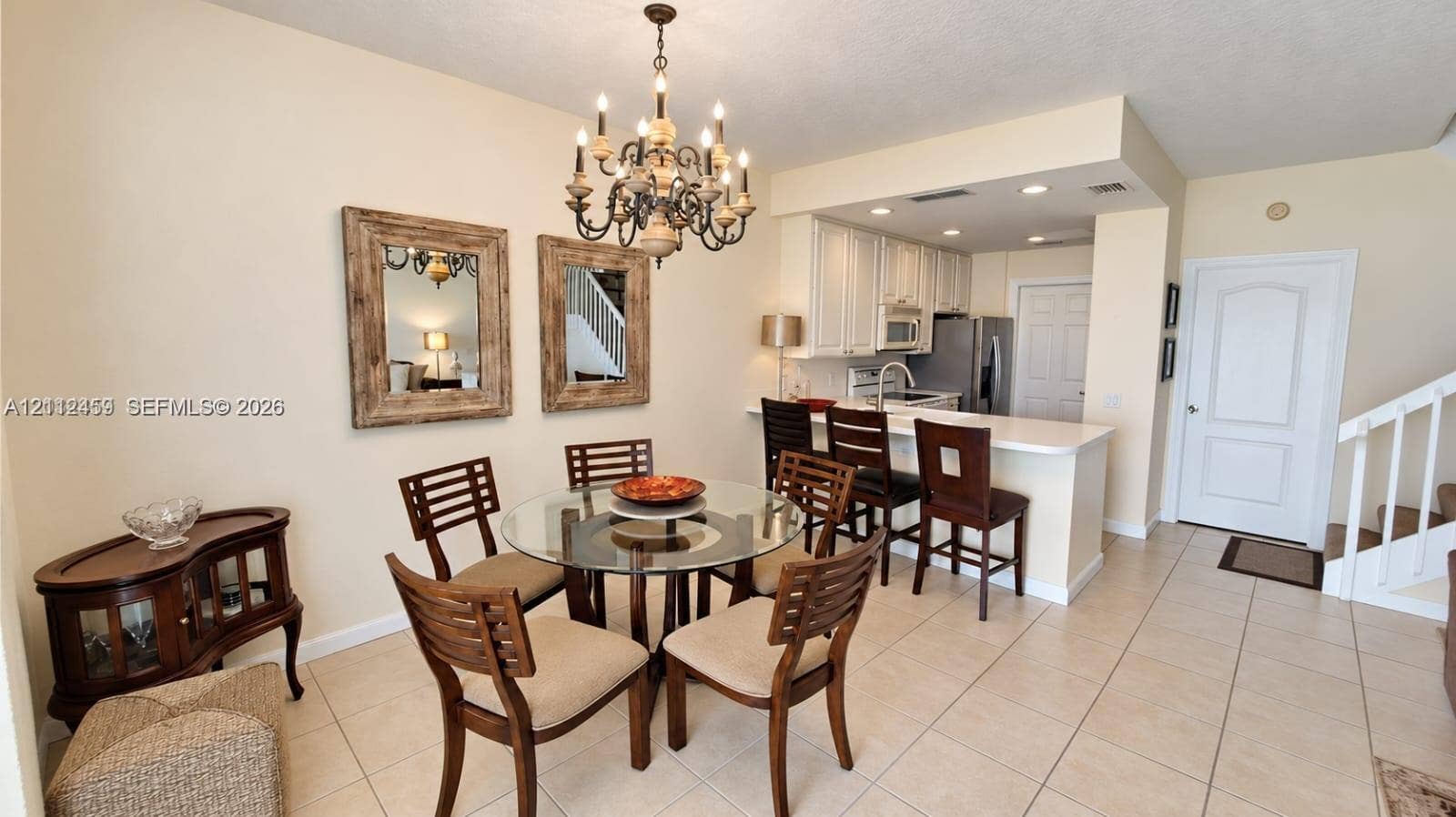 Open-concept kitchen featuring white shaker-style cabinetry, stainless steel appliances, and a solid-surface breakfast bar