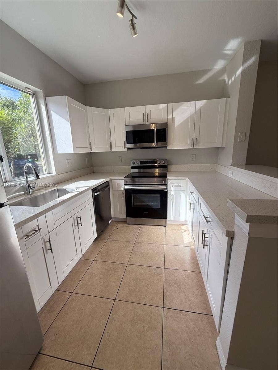 20439 NW 15th Avenue, #9, Miami Gardens, Miami Gardens, FL 33169 Kitchen featuring white shaker-style cabinetry, stainless steel appliances, neutral countertops, tile flooring, and a single-basin undermount sink